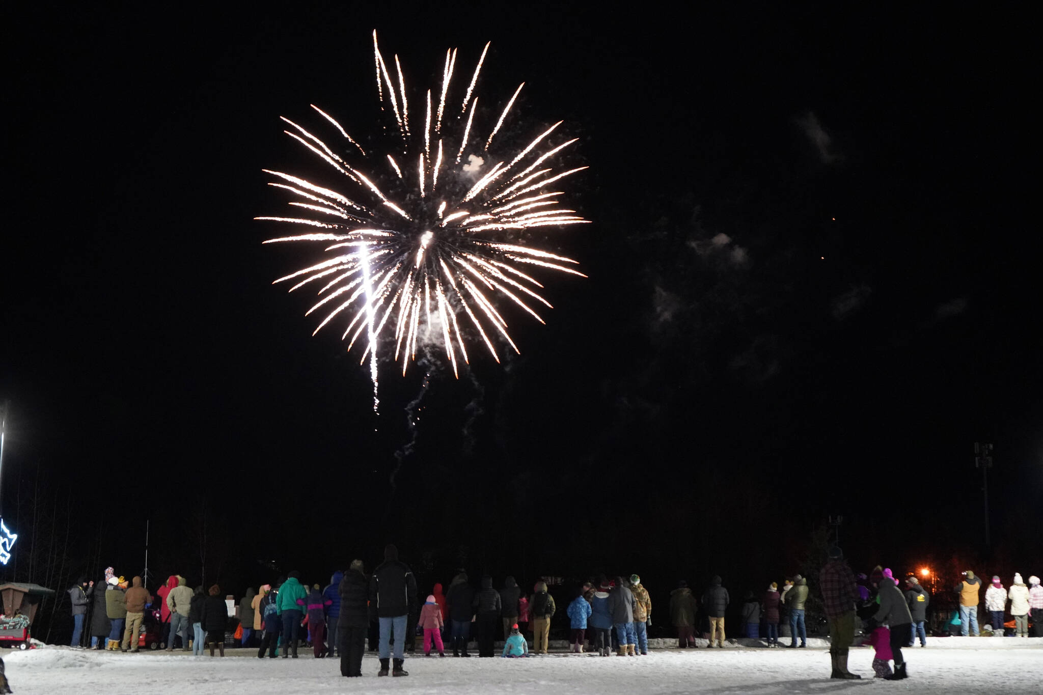 Attendees line the edge of Soldotna Creek Park in Soldotna, Alaska, to see fireworks over the Kenai River during Christmas in the Park festivities on Saturday, Dec. 2, 2023. (Jake Dye/Peninsula Clarion)
