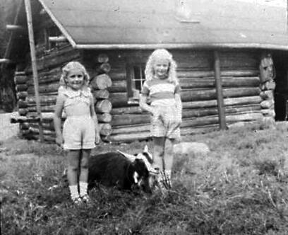 Photo courtesy of the Mullen Family Collection via the Kenai Peninsula College historical photo repository
In the early 1950s, the Marge and Frank Mullen family were offered a chance to stay in the Marcus Bodnar cabin, which was much more spacious than their own. The Bodnar brothers had decided to move to Anchorage to earn some wages. Here, Eileen (L) and Peggy Mullen pose with their goats outside Marcus’s cabin in about 1951.