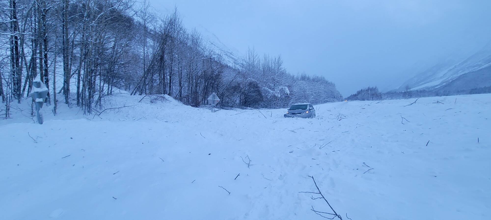 A vehicle is surrounded by avalanche debris along the Seward Highway on Sunday, Dec. 24, 2023 near Cooper Landing, Alaska. (Photo courtesy Alaska Department of Transportation and Public Facilities)