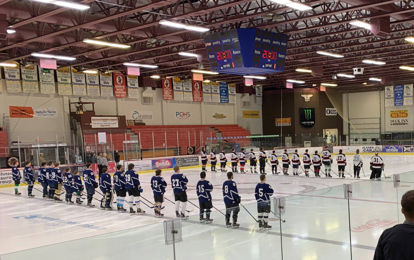 Hockey players in the annual Kenai/Niksiki and SoHi/Skyview alumni hockey game stand for the national anthem at the Soldotna Regional Sports Complex on Friday, Dec. 22, 2023 in Soldotna, Alaska. (Ashlyn O’Hara/Peninsula Clarion)