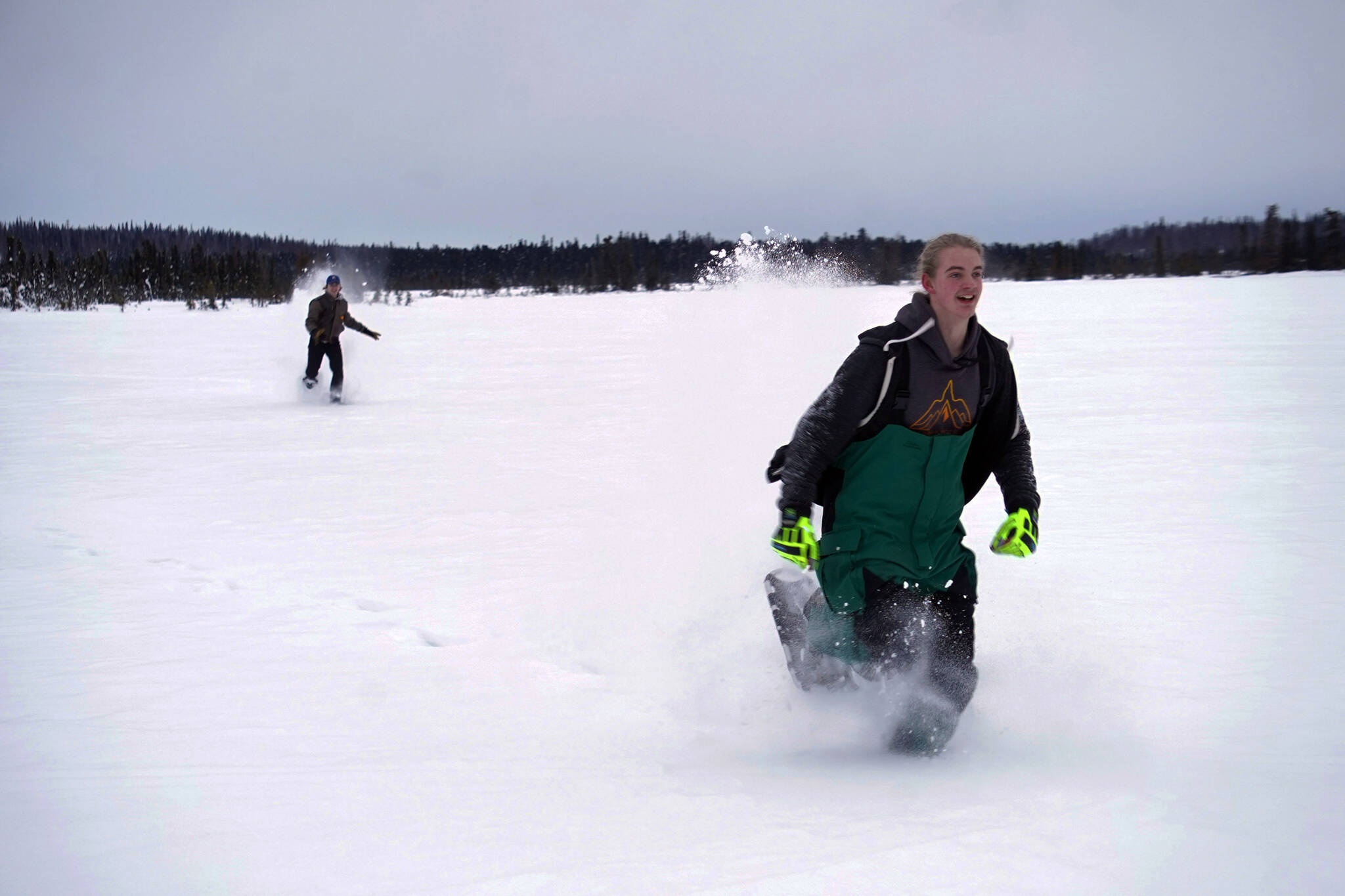 Nathan Teates uses snowshoes to run across Headquarters Lake in the Kenai National Wildlife Refuge, pursued by Isaac Copple, near Soldotna, Alaska, on Saturday, Jan. 6, 2024. (Jake Dye/Peninsula Clarion)