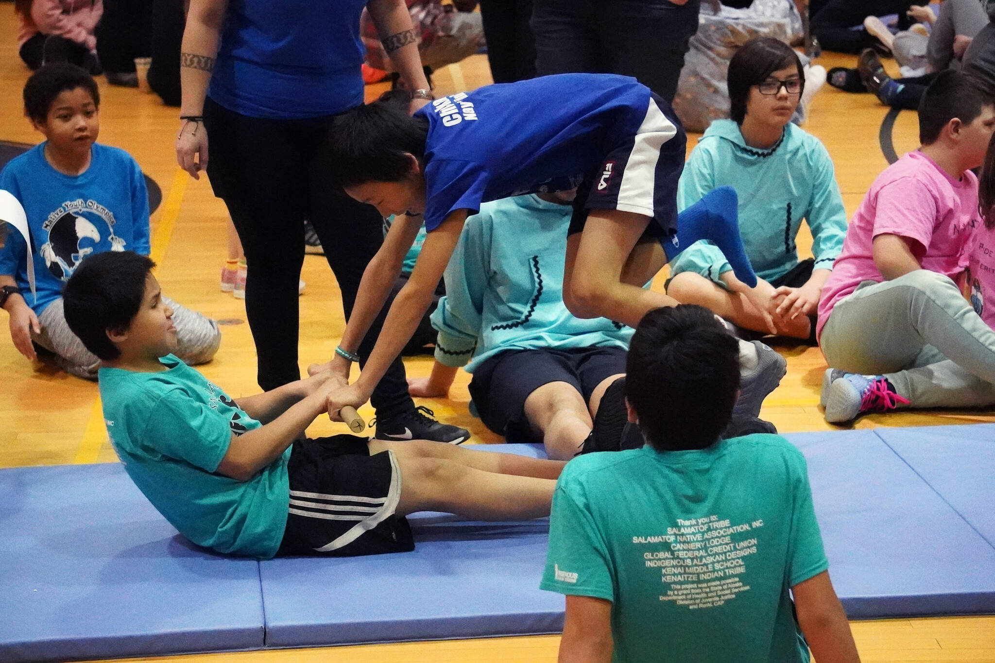 Bryce Butler pulls an athlete from Chickaloon up and over to win a round of the Inuit stick pull during the Kahtnuht’ana Hey Chi’ula Native Youth Olympics Invitational at Kenai Middle School in Kenai, Alaska, on Saturday, Jan. 13, 2024. (Jake Dye/Peninsula Clarion)