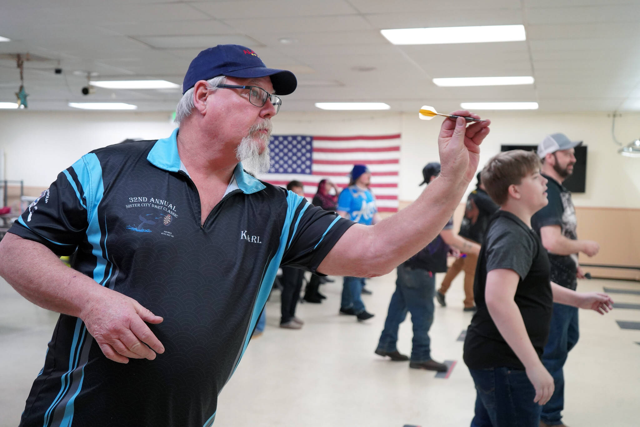 Karl Schmidt readies to loose a dart at the Elks Lodge in Kenai, Alaska, on Saturday, Feb. 3, 2024. (Jake Dye/Peninsula Clarion)