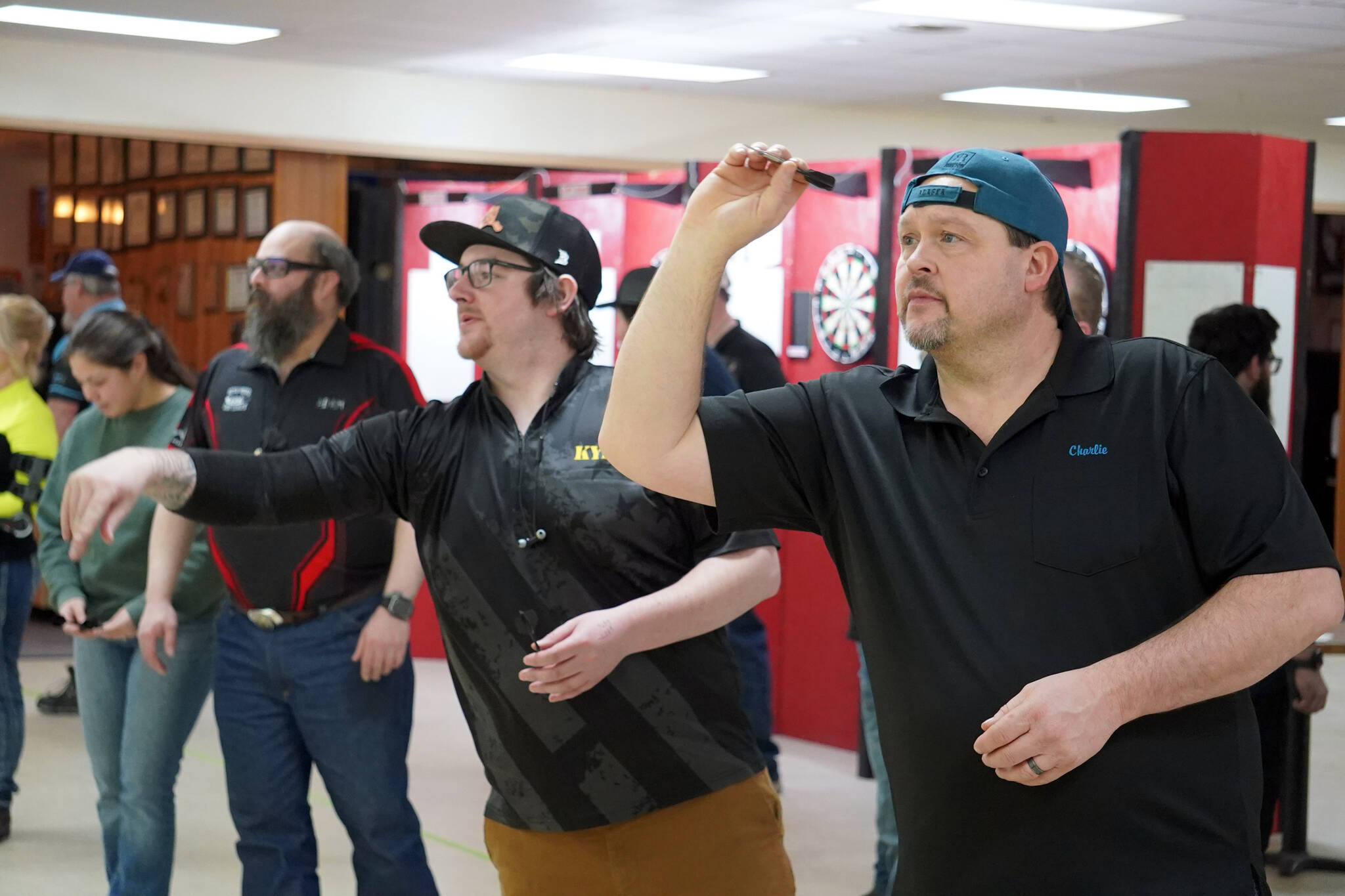 Charlie Mathis, right, readies to loose a dart at the Elks Lodge in Kenai, Alaska, on Saturday, Feb. 3, 2024. (Jake Dye/Peninsula Clarion)