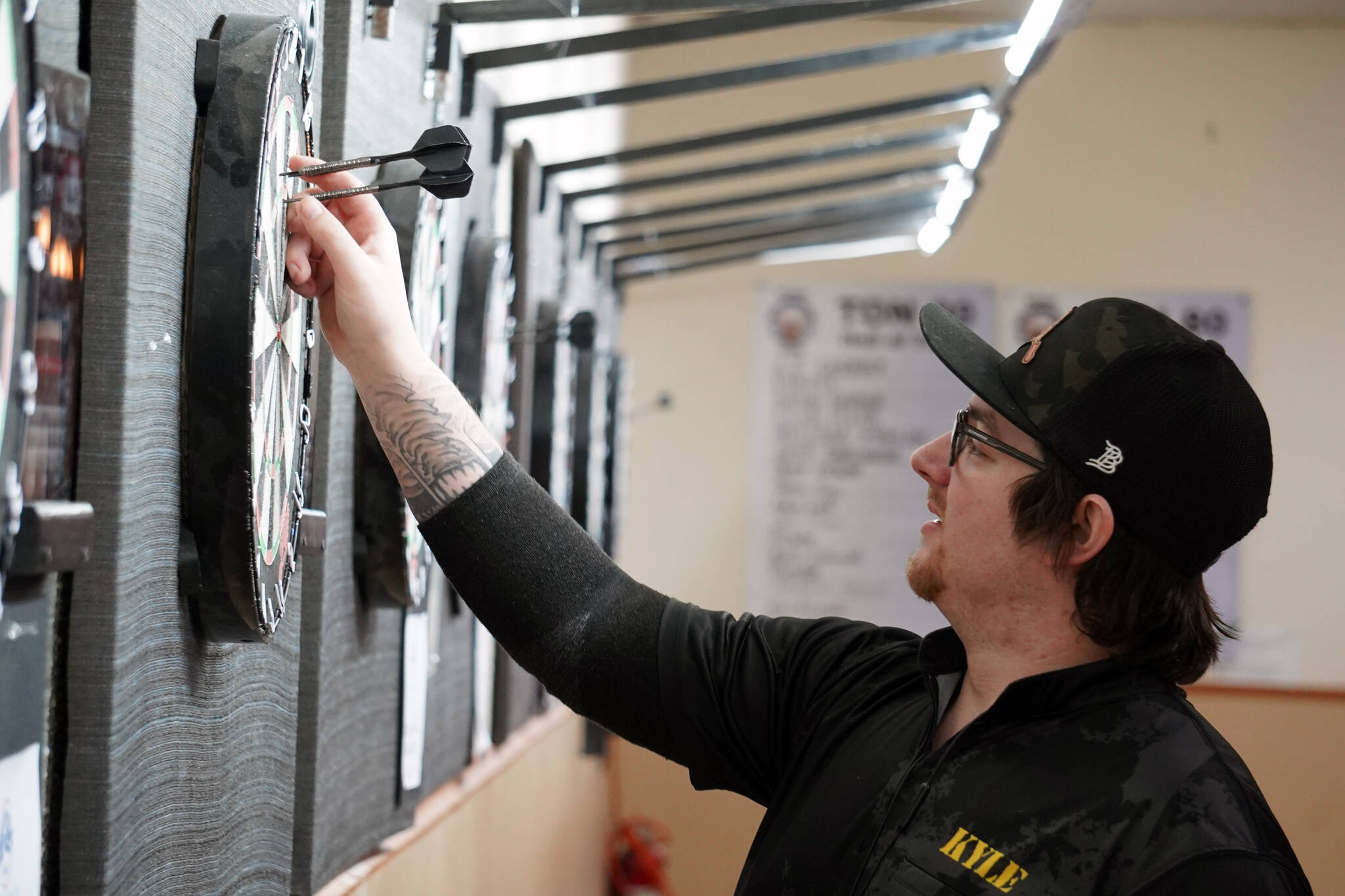 Kyle Olson pulls his darts from a board at the Elks Lodge in Kenai, Alaska, on Saturday, Feb. 3, 2024. (Jake Dye/Peninsula Clarion)