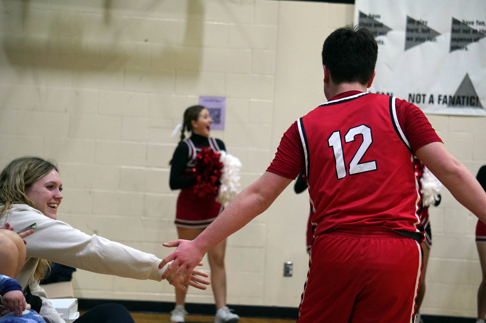Kenai’s Connor Ley collects high fives from the bleachers after making an unlikely shot during a basketball game at Nikiski Middle/High School in Nikiski, Alaska, on Tuesday, Feb. 20, 2024. (Jake Dye/Peninsula Clarion)