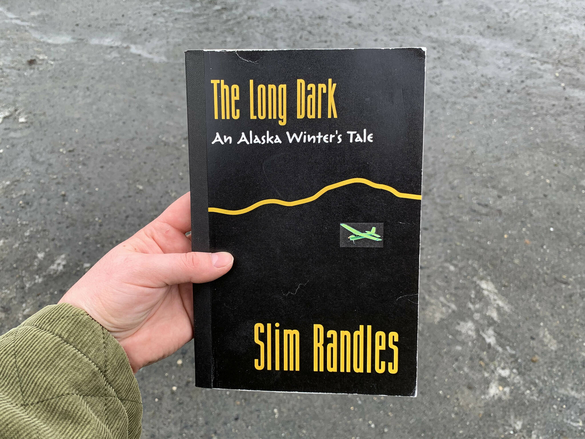 A copy of Slim Randles’ “The Long Dark: An Alaska Winter’s Tale” is held on Wednesday, April 27, 2024, near Soldotna, Alaska. (Ashlyn O’Hara/Peninsula Clarion)