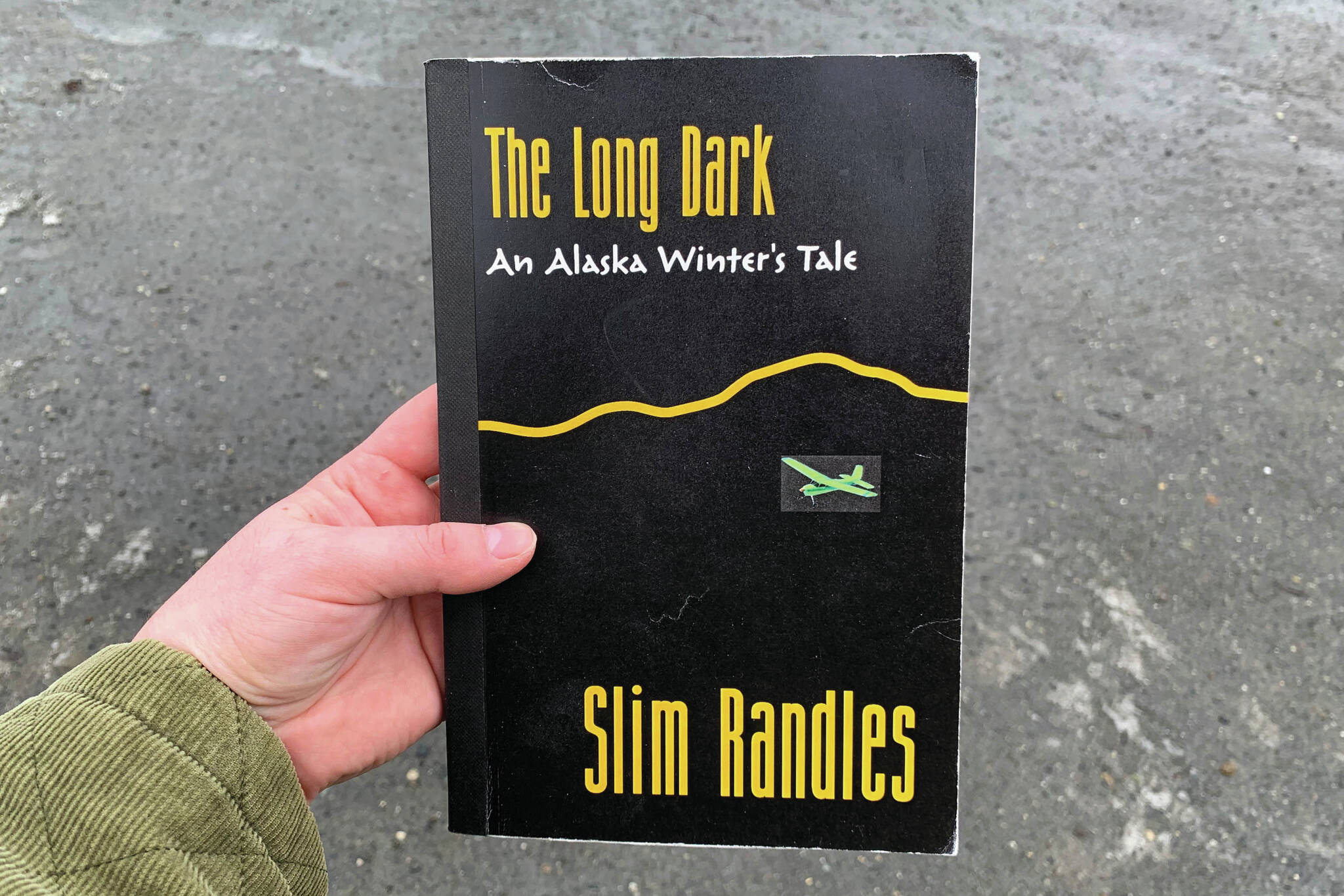 A copy of Slim Randles’ “The Long Dark: An Alaska Winter’s Tale” is held on Wednesday, April 27, 2024, near Soldotna, Alaska. (Ashlyn O’Hara/Peninsula Clarion)