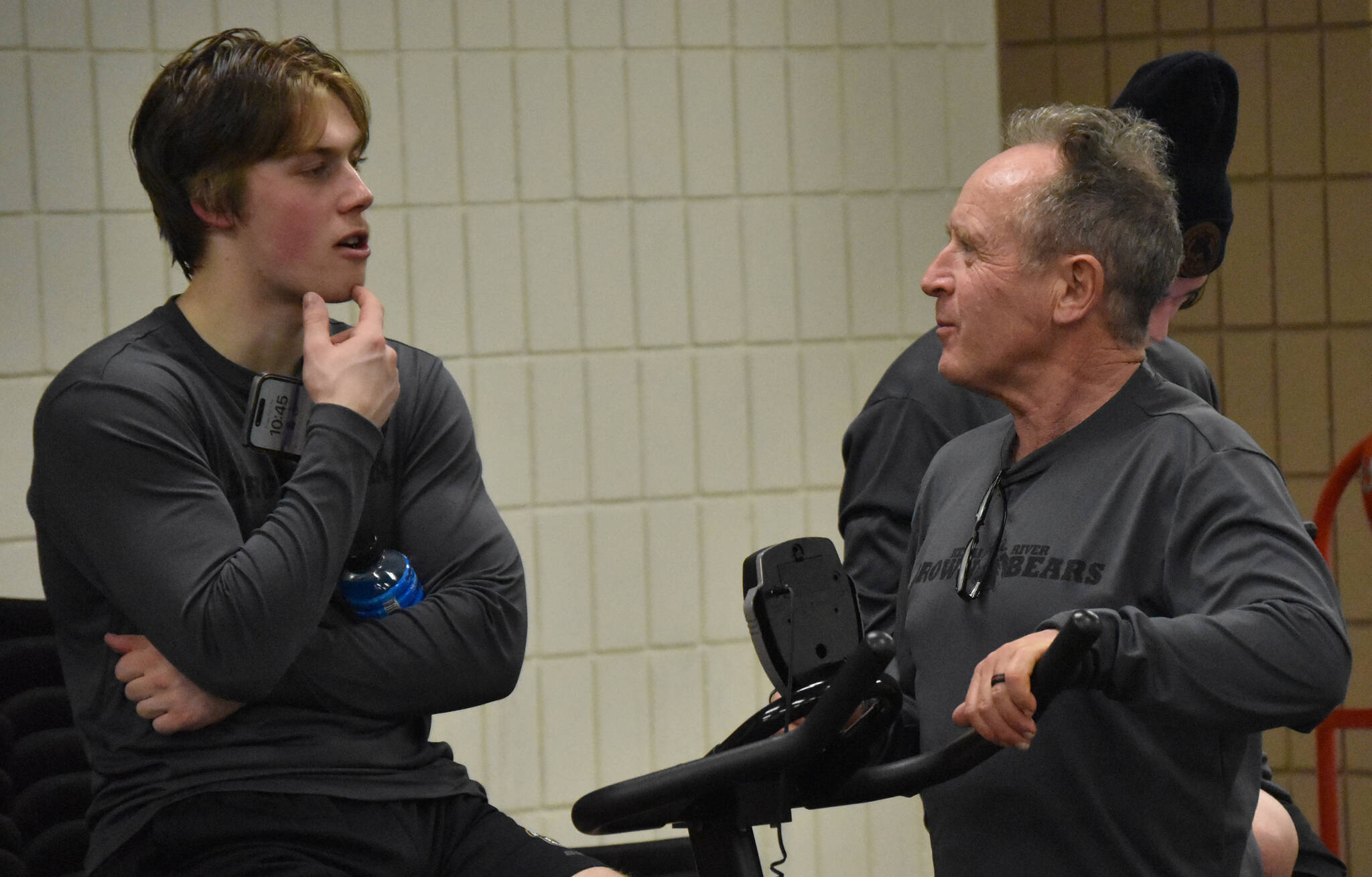 John Bryan, Co-Director of Sports Science, Strength and Conditioning for the Kenai River Brown Bears, talks with Andy Larson as he cool down on the bike after a game at the Soldotna Regional Sports Complex in Soldotna, Alaska, on Friday, March 29, 2024. (Photo by Jeff Helminiak/Peninsula Clarion)
