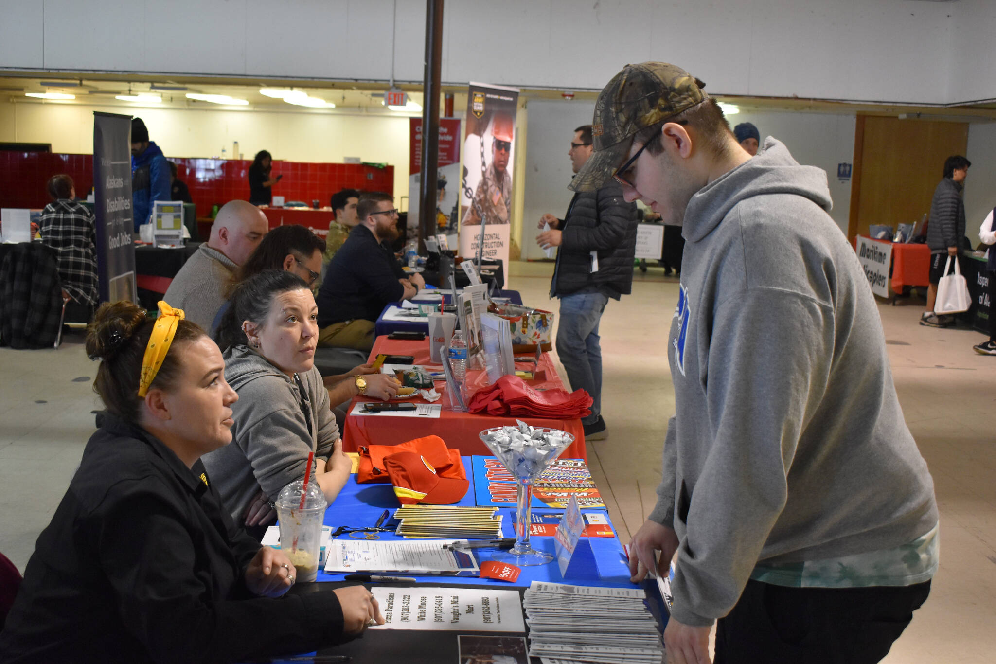 A visitor to the 2023 Kenai Peninsula Job and Career Fair speaks to representatives of Paradisos Restaurant on Thursday, April 6, 2023 at the Old Carrs Mall in Kenai, Alaska. (Jake Dye/Peninsula Clarion)