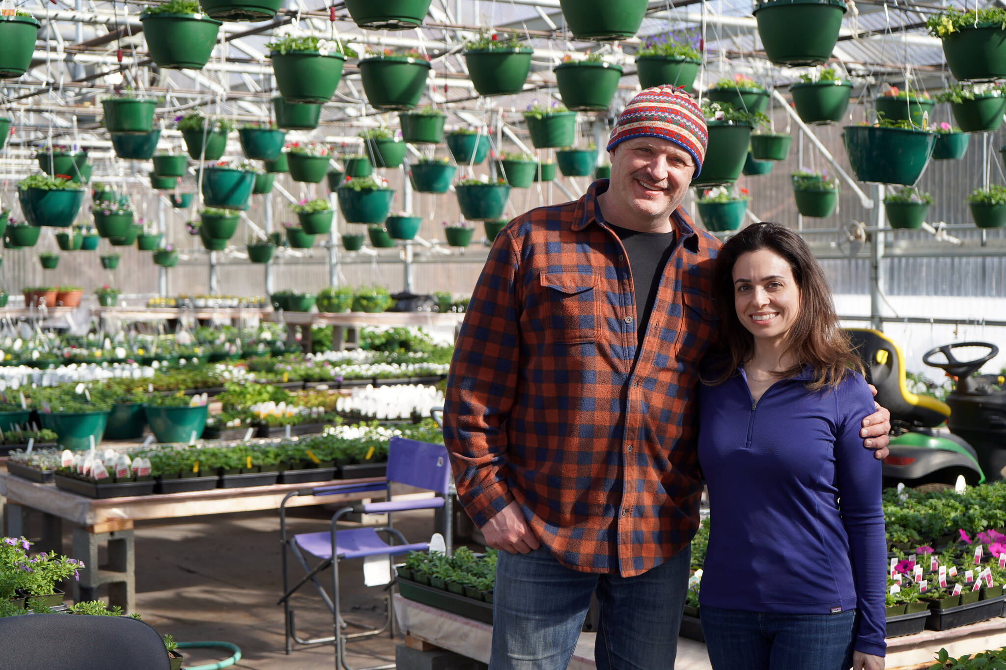 John and Parrisa Harris are surrounded by plants and flowers in the newly reopened Fireweed Greenhouse in Kenai, Alaska, on Sunday, April 7, 2024. (Jake Dye/Peninsula Clarion)