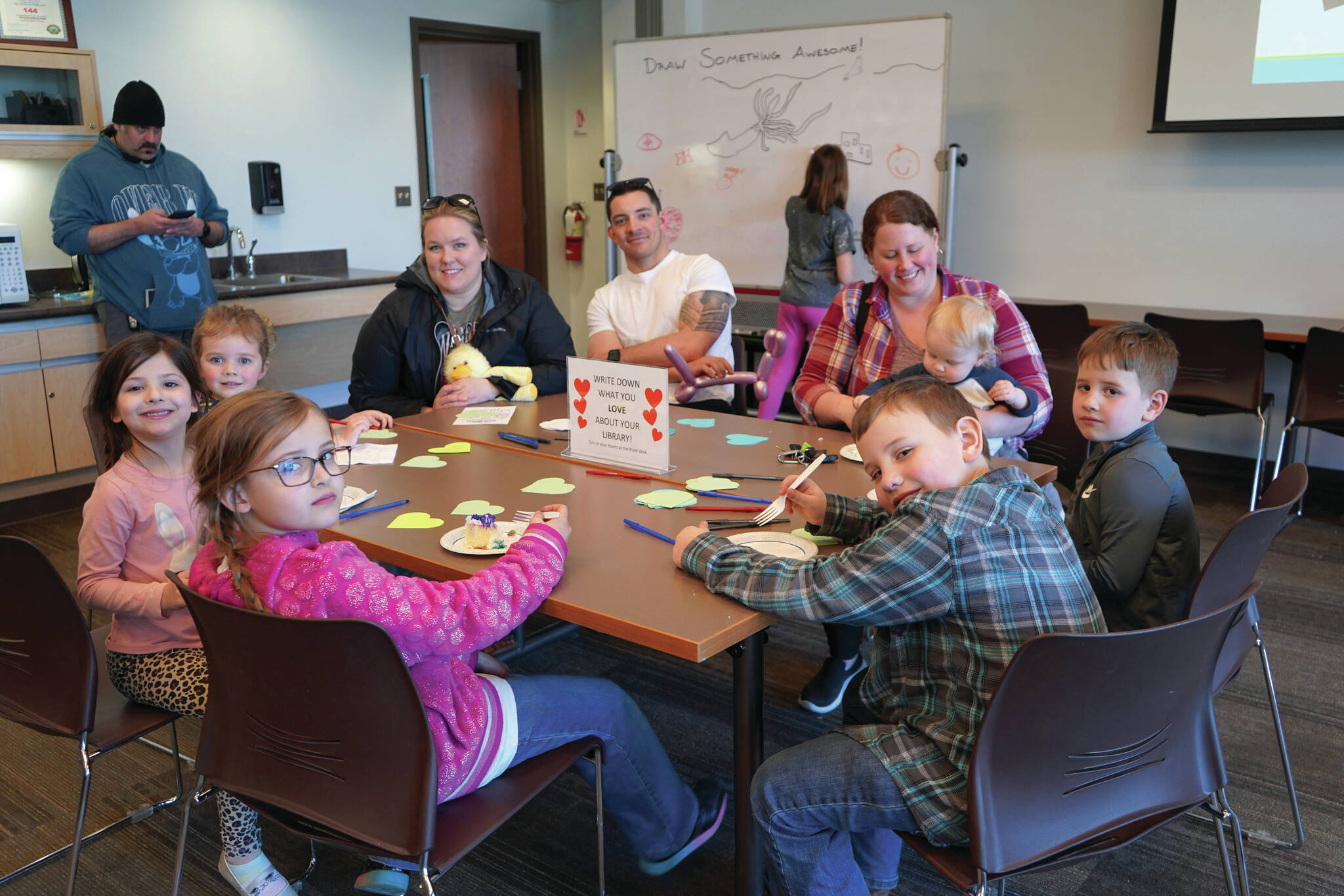 Jake Dye/Peninsula Clarion
Children and families gather around a table to eat cake and write down what they love about their library at a 10th anniversary celebration for the expansion of the Soldotna Public Library on Monday.