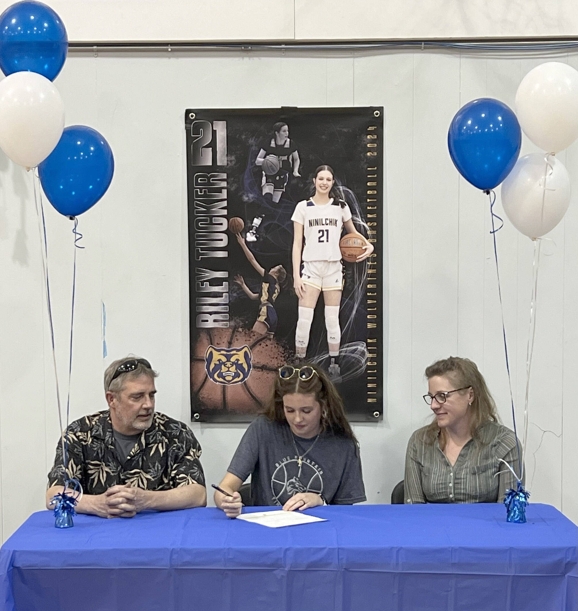 Riley Tucker signs a National Letter of Intent to play basketball at Blue Mountain Community College in Oregon on Monday, April 29, 2024, at Ninilchik School in Ninilchik, Alaska. At left is Riley’s father, Tony Tucker, and at right is Riley’s mother, Danielle Tucker. (Photo provided)