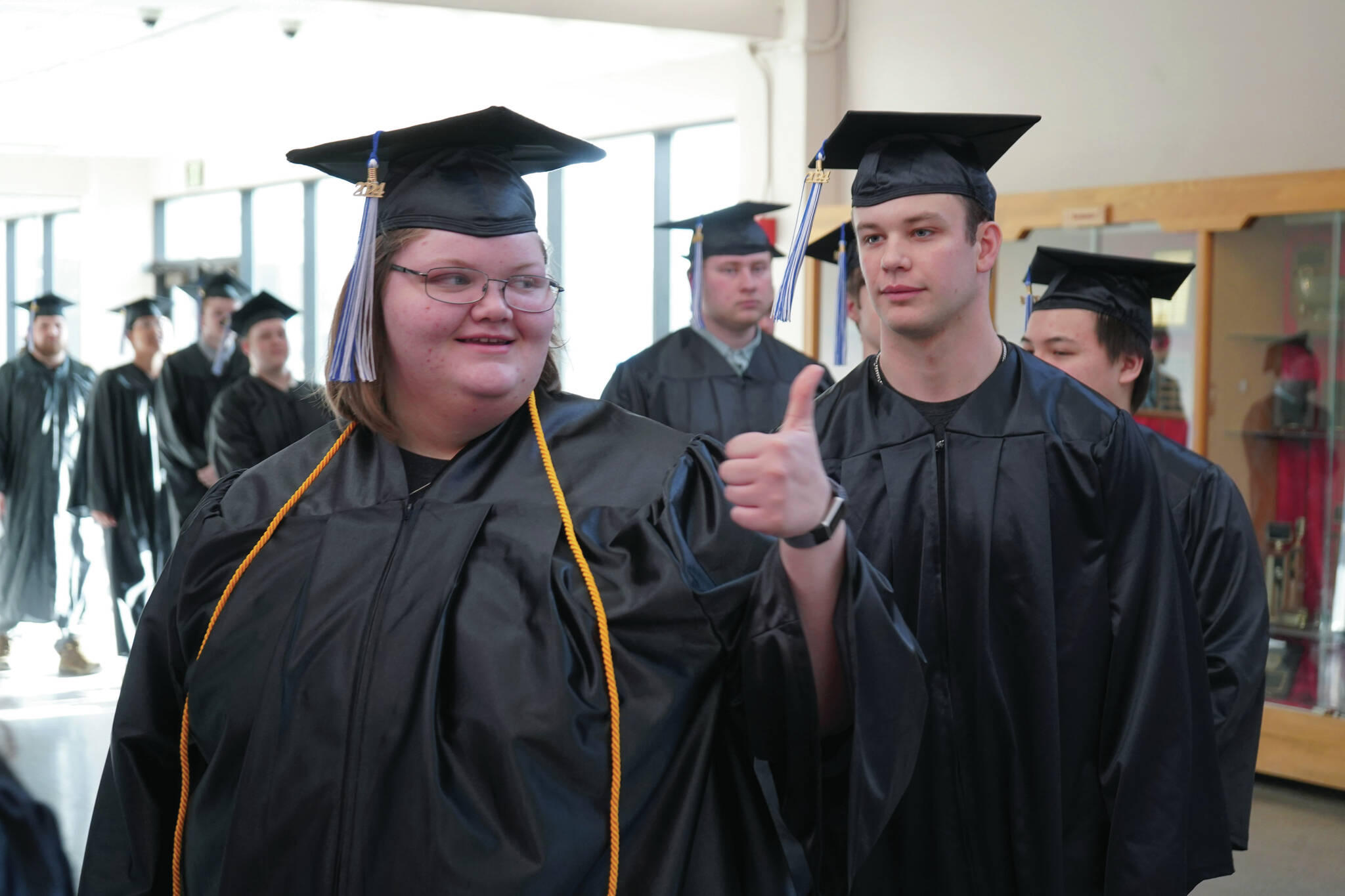 A graduate of Kenai Peninsula College gives a thumbs up as graduates proceed into the 54th Annual Kenai Peninsula College Commencement Ceremony at Kenai Central High School on Thursday. (Jake Dye/Peninsula Clarion)