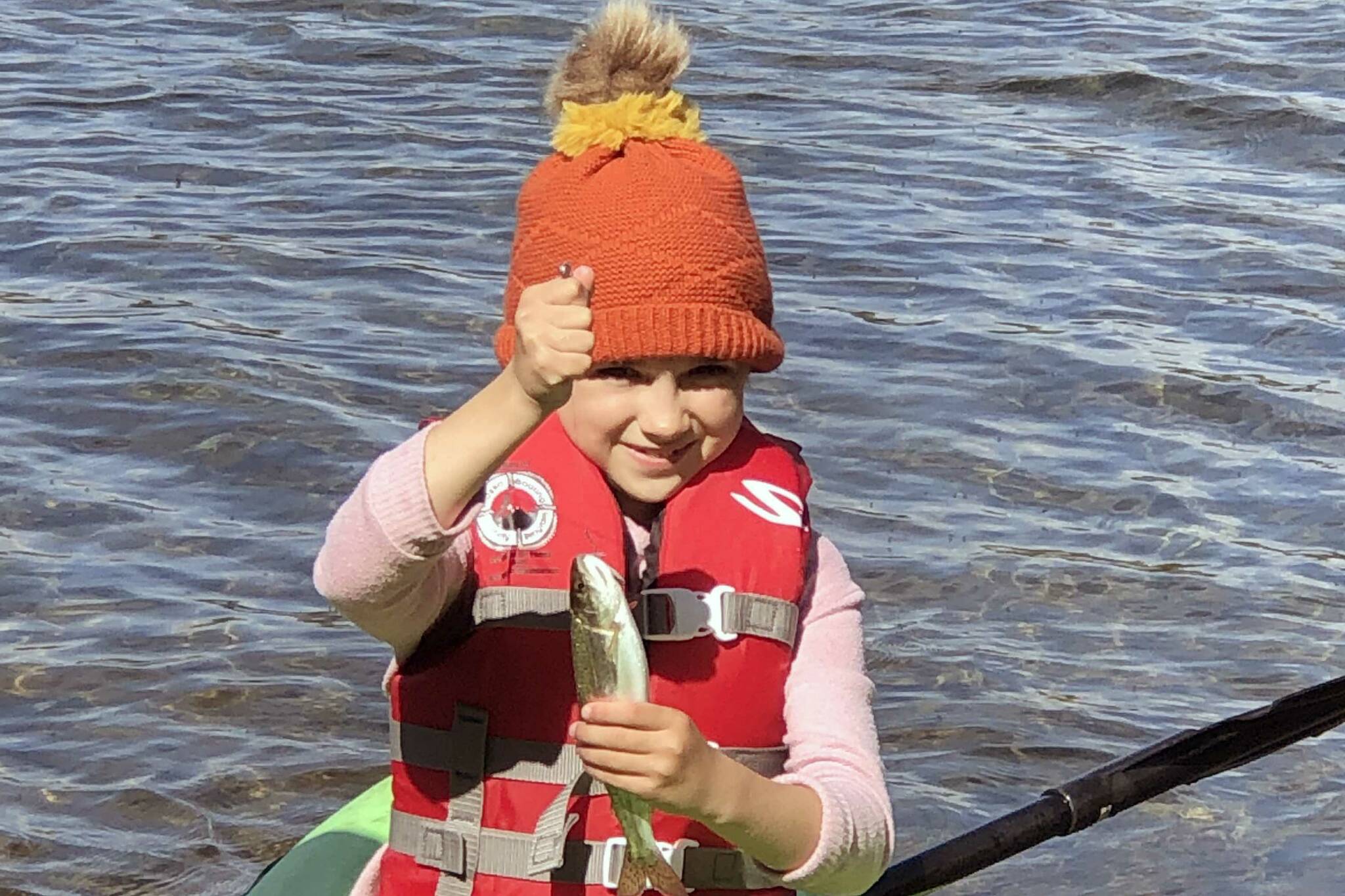 If you teach a kid to fish, she will feed you a trout breakfast every morning of the campout. This proved true for this girl, who holds up a rainbow trout while sitting on a kayak. (Photo by Leah Eskelin)