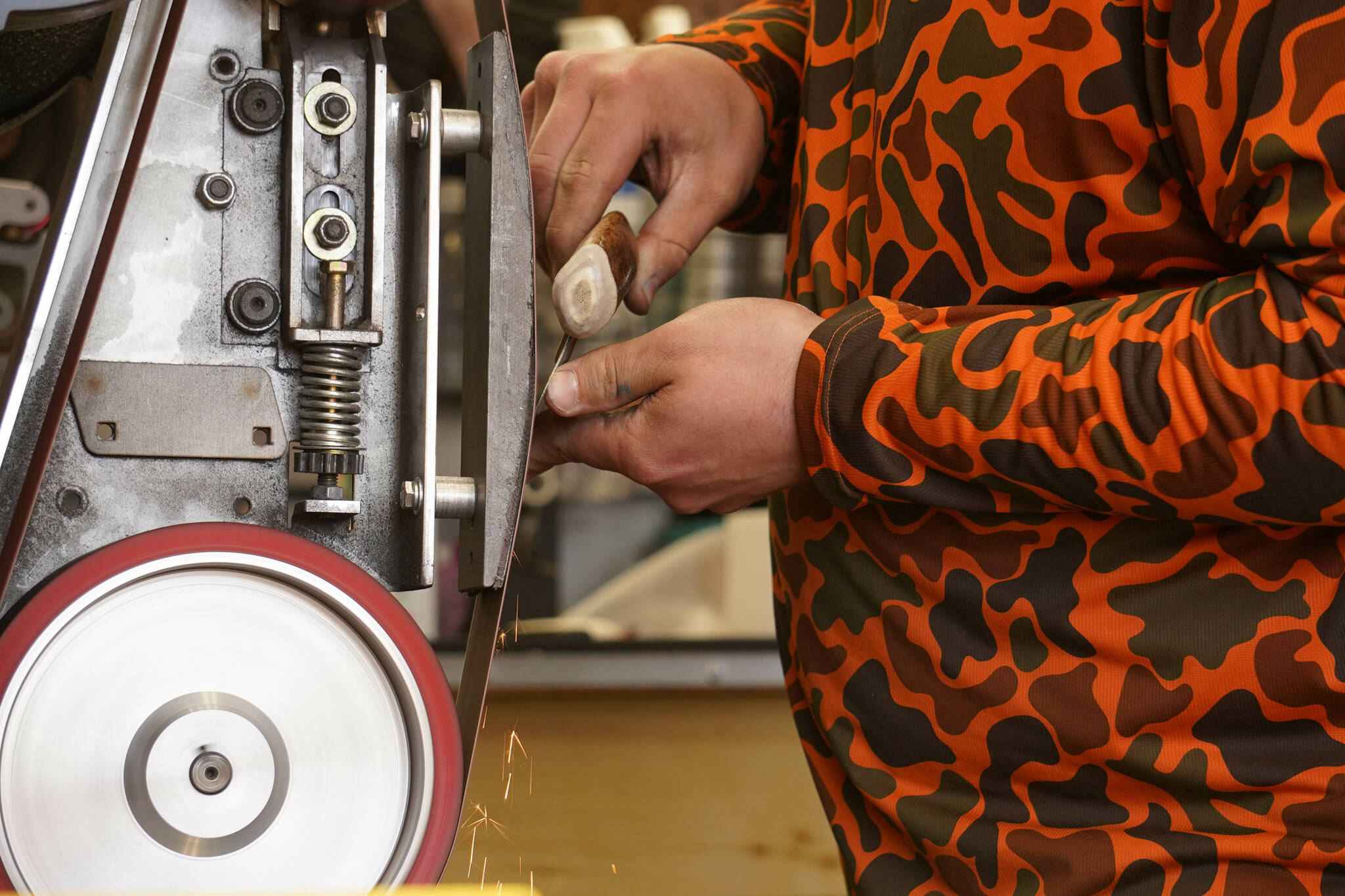 Grey Wilson, of Wilson’s Proper Edge, sharpens an ulu at Soldotna Creek Park in Soldotna, Alaska, on Wednesday, June 19, 2024. (Jake Dye/Peninsula Clarion)