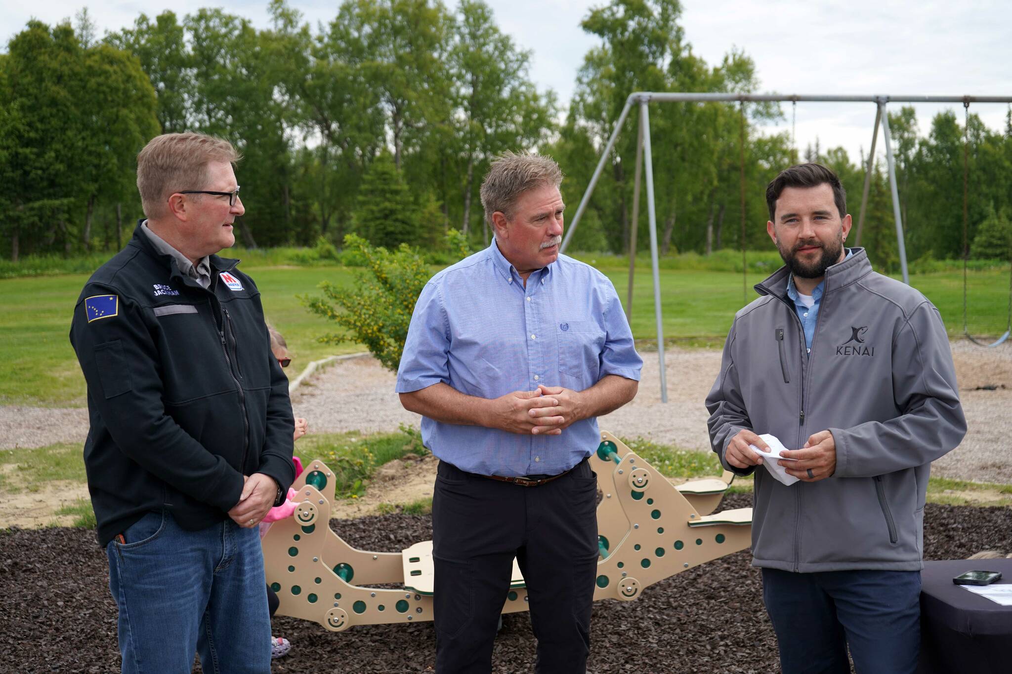 Marathon Kenai refinery General Manager Bruce Jackman, City of Kenai Mayor Brian Gabriel and Kenai Parks and Recreation Director Tyler Best speak at an event celebrating the installation of a new inclusive seesaw at Kenai Municipal Park in Kenai, Alaska, on Thursday, June 27, 2024. (Jake Dye/Peninsula Clarion)