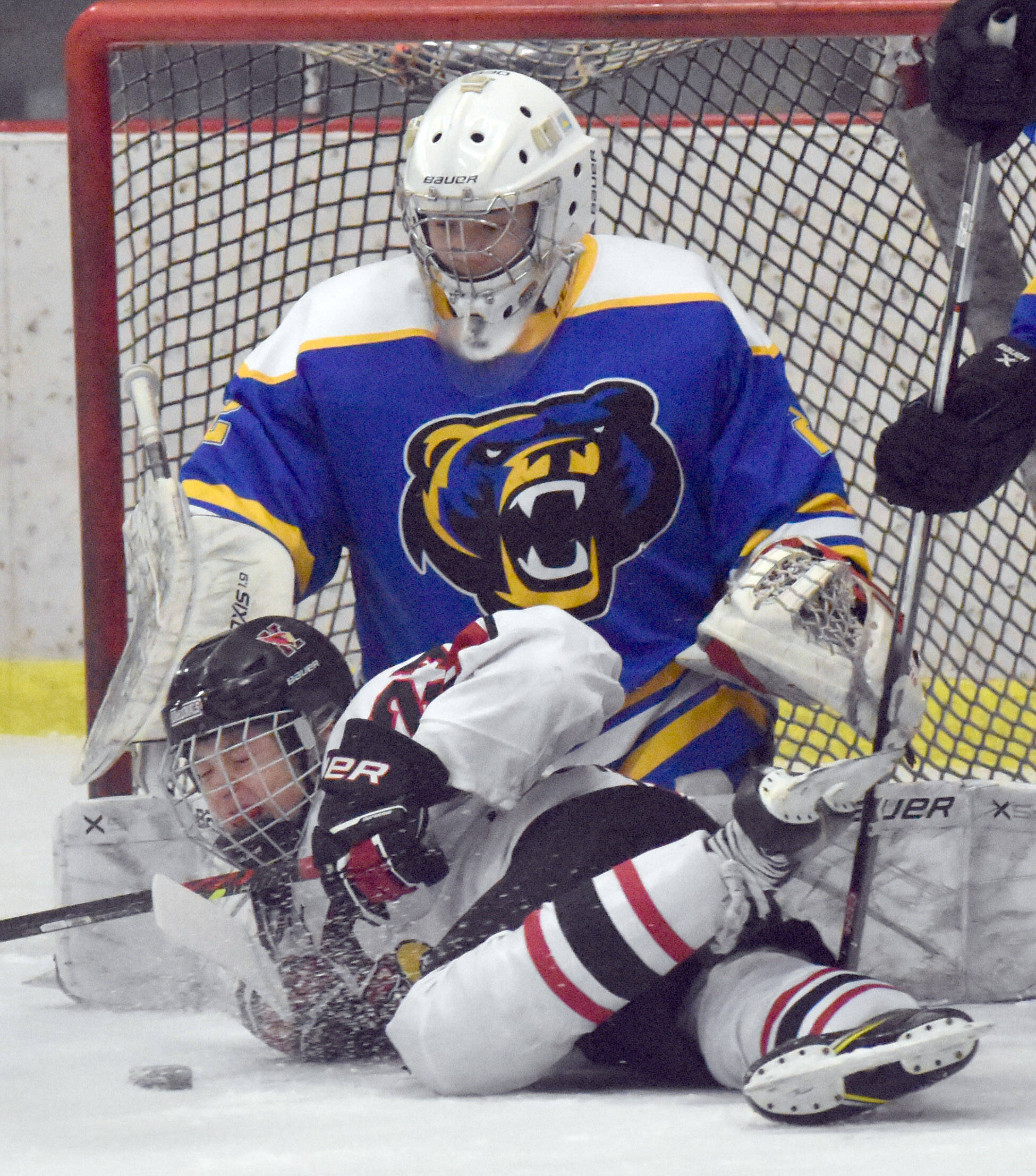 Kenai Central’s Noah Hallam battles for the puck in front of Kodiak goalie Garrett Wood on Thursday, Dec. 12, 2024, at the Kenai Multi-Purpose Facility in Kenai, Alaska. (Photo by Jeff Helminiak/Peninsula Clarion)
