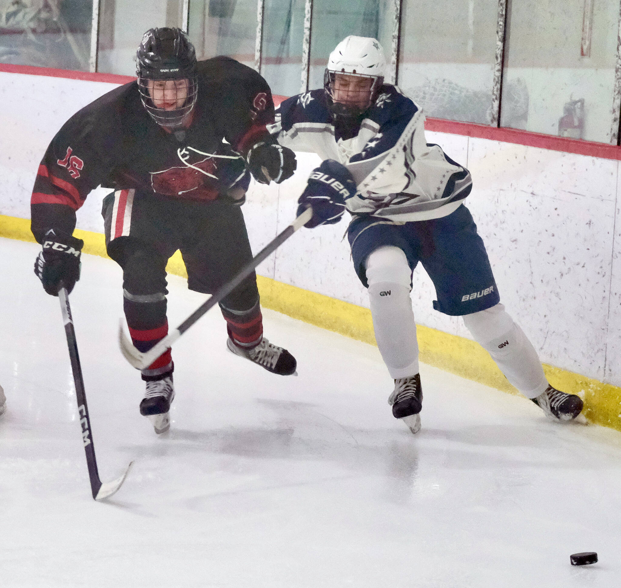 Juneau-Douglas senior Ike Puustinen (16) works for a puck against Soldotna’s Eli Settlemyer (28) during a 4-3 Crimson Bears loss to the visiting Stars at Treadwell Ice Arena in Juneau, Alaska, on Friday, Dec. 13, 2024. (Klas Stolpe / Juneau Empire)