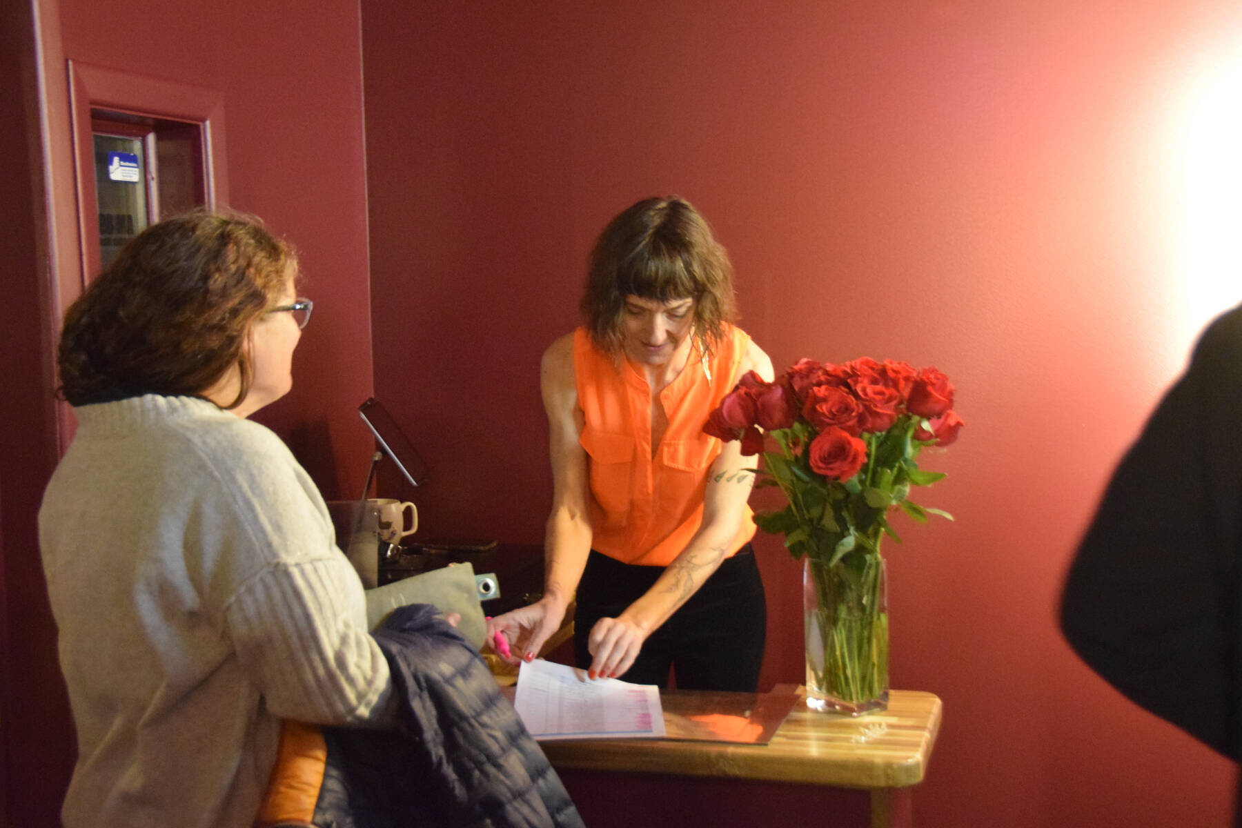 Co-owner Susannah Webster (right) checks in another attendee of The Porcupine Theater’s grand reopening gala on Friday, Jan. 31, 2025, in Homer, Alaska. (Delcenia Cosman/Homer News)