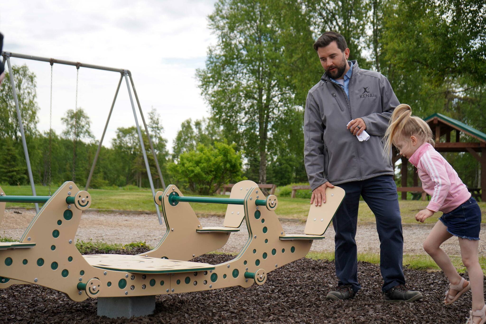 Kenai Parks and Recreation Director Tyler Best shows off a new inclusive seesaw at Kenai Municipal Park in Kenai, Alaska, on Thursday, June 27, 2024. (Jake Dye/Peninsula Clarion)