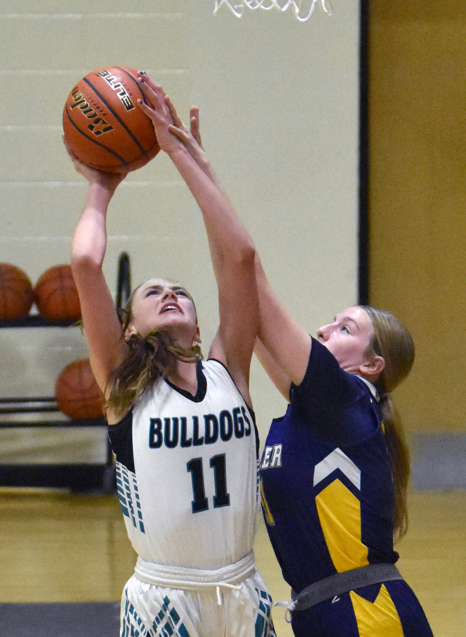 Nikiski’s Blakeley Jorgensen is fouled by Homer’s Keagan Niebuhr on Tuesday, February 11, 2025, at Nikiski Middle-High School in Nikiski, Alaska. (Photo by Jeff Helminiak/Peninsula Clarion)
