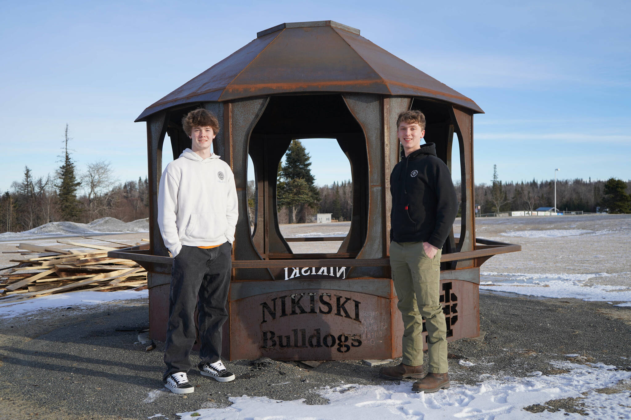 Gavin Ley and Noah Douglas stand with a firepit they designed and installed with other students in the career and technical education courses at Nikiski Middle/High School in Nikiski, Alaska, on Tuesday, Feb. 11, 2025. (Jake Dye/Peninsula Clarion)