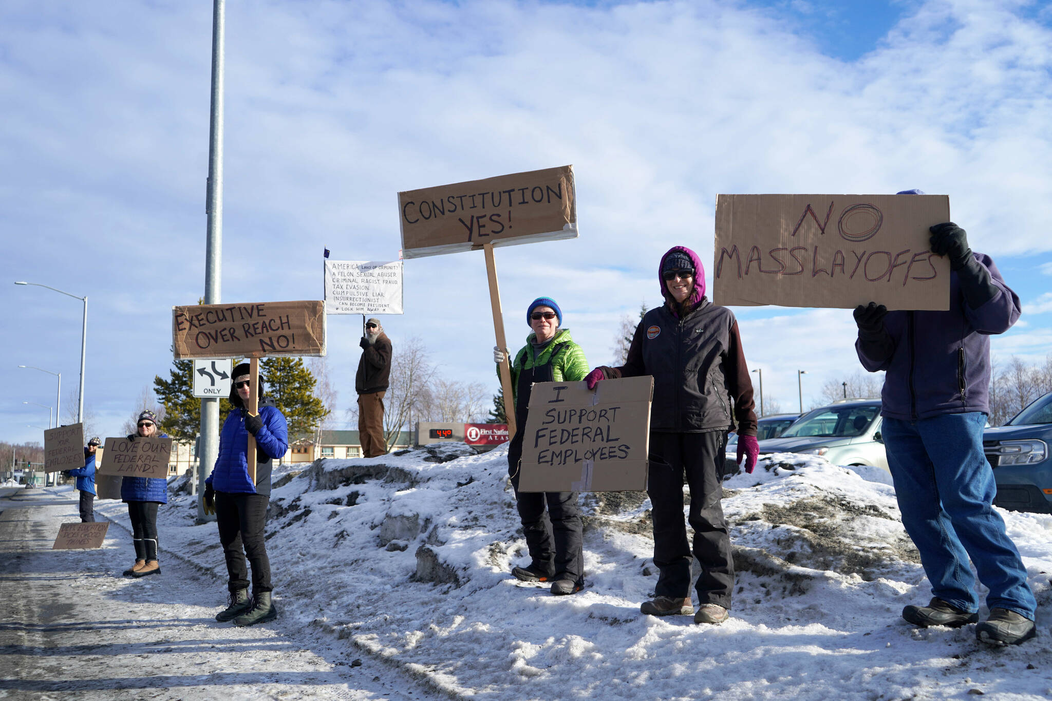 Protesters stand with signs in support of federal employees, federal lands and the U.S. Constitution stand along the Sterling Highway in Soldotna, Alaska, on Monday, Feb. 17, 2025. (Jake Dye/Peninsula Clarion)