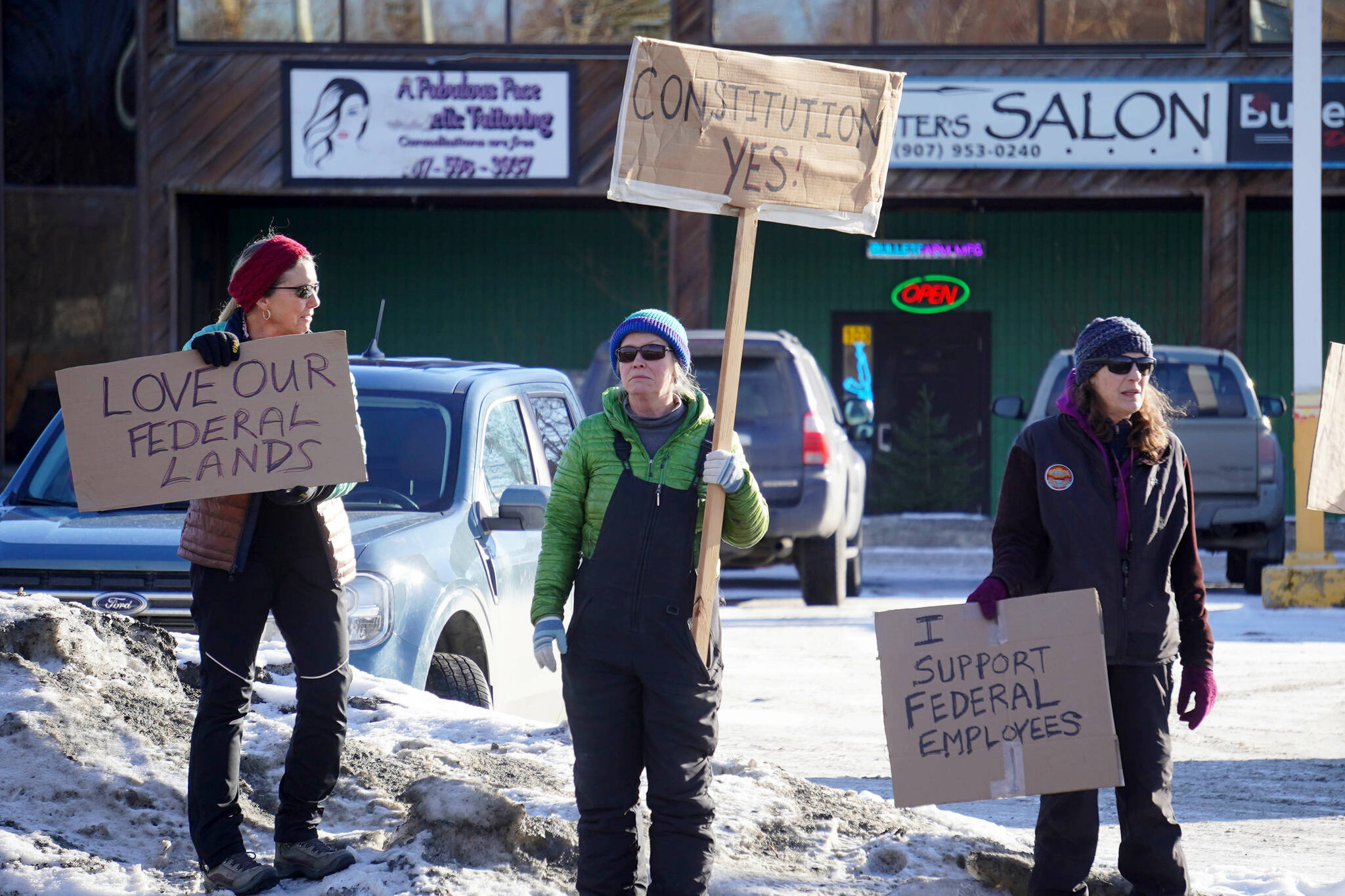 Protesters stand with signs in support of federal employees, federal lands and the U.S. Constitution stand along the Sterling Highway in Soldotna, Alaska, on Monday, Feb. 17, 2025. (Jake Dye/Peninsula Clarion)