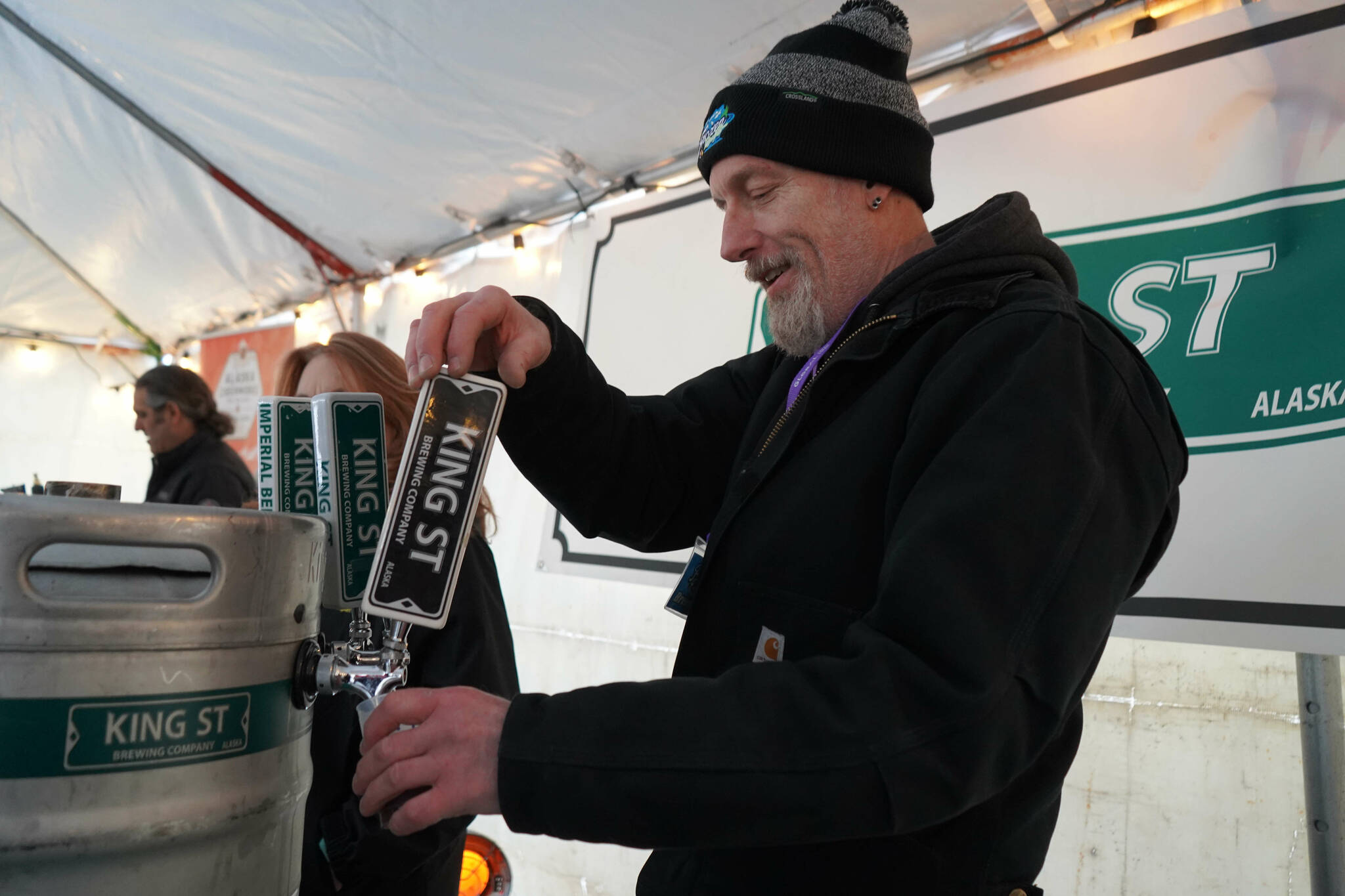 A brewer from King Street Brewing Company pours a cup for an attendee at the 10th Annual Frozen River Fest in Soldotna, Alaska, on Saturday, Feb. 15, 2025. (Jake Dye/Peninsula Clarion)