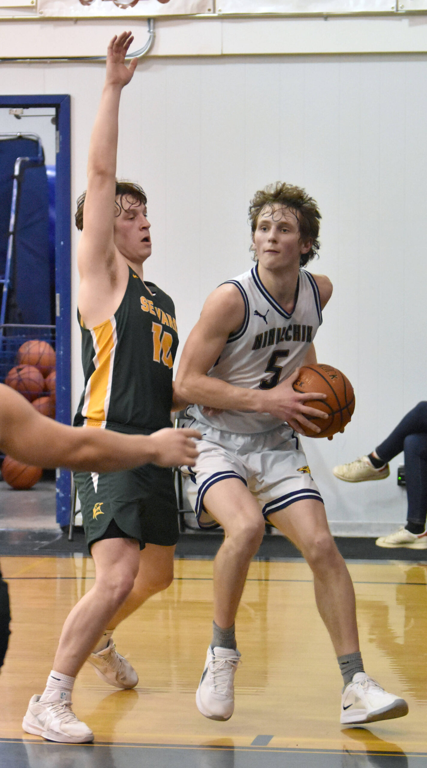 Ninilchik’s Kade McCorison drives on Seward’s Emerson Cross on Friday, February 21, 2025, at Ninilchik School in Ninilchik, Alaska. (Photo by Jeff Helminiak/Peninsula Clarion)