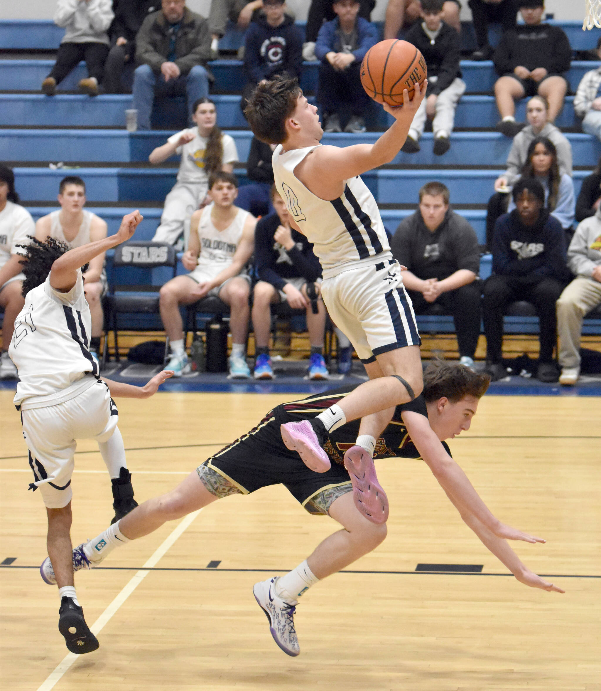 Soldotna’s Easton Hawkins attacks the basket as Soldotna’s Izaiah Gilbert and Grace Christian’s Bristol Tobin get tangled Saturday, Feb. 22, 2025, at Soldotna High School in Soldotna, Alaska. (Photo by Jeff Helminiak/Peninsula Clarion)