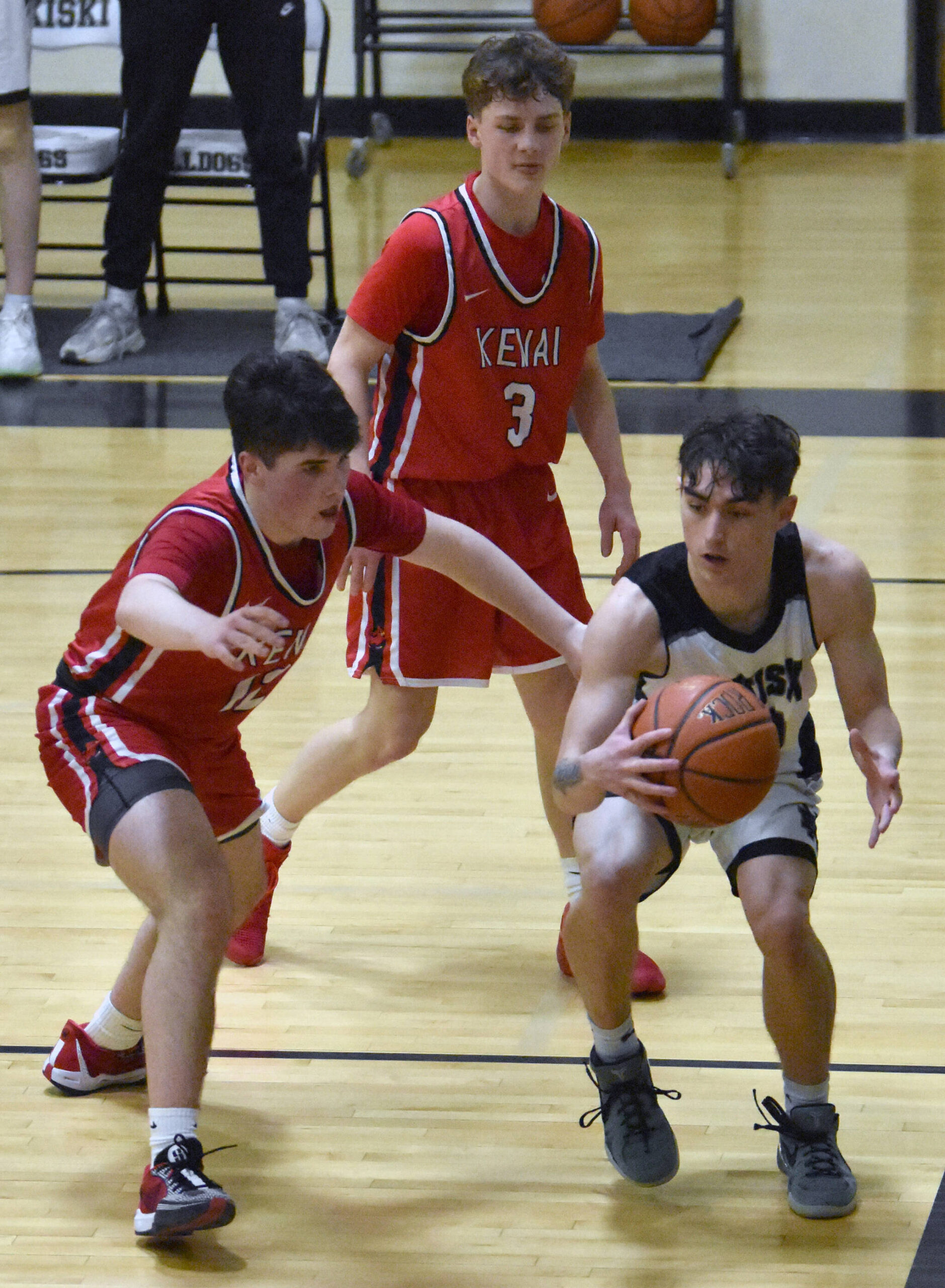 Nikiski’s Dylan Hall battles against a trap by Kenai Central’s Reid Titus and Carter Felchle on Friday, March 7, 2025, at the Peninsula Conference tournament at Nikiski Middle-High School in Nikiski, Alaska. (Photo by Jeff Helminiak/Peninsula Clarion)