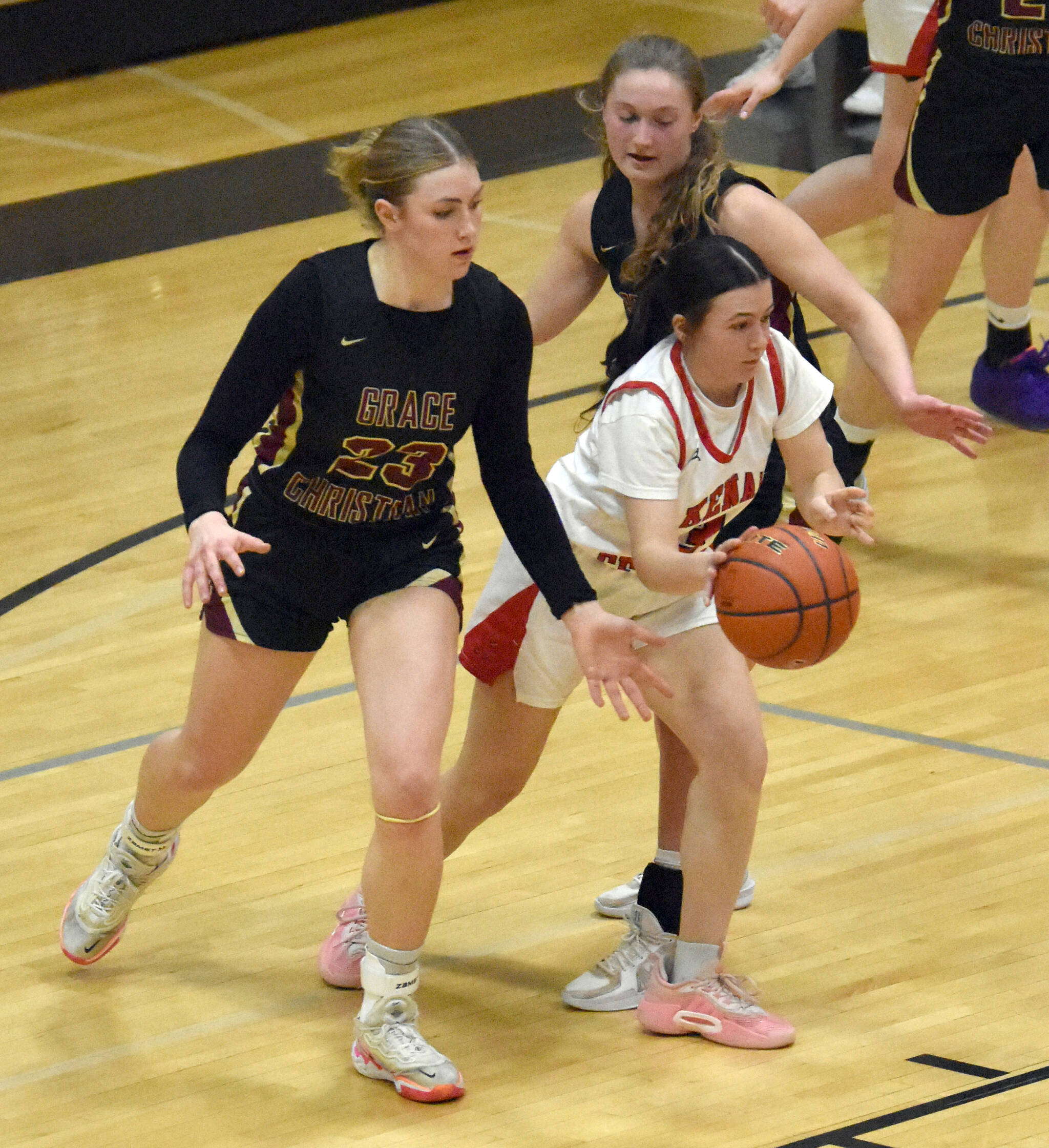 Kenai Central’s Evelyn Cooper passes under pressure from Grace Christian’s Sophie Lentfer and Hope Jackson on Saturday, March 8, 2025, at the Peninsula Conference tournament at Nikiski Middle-High School in Nikiski, Alaska. (Photo by Jeff Helminiak/Peninsula Clarion)