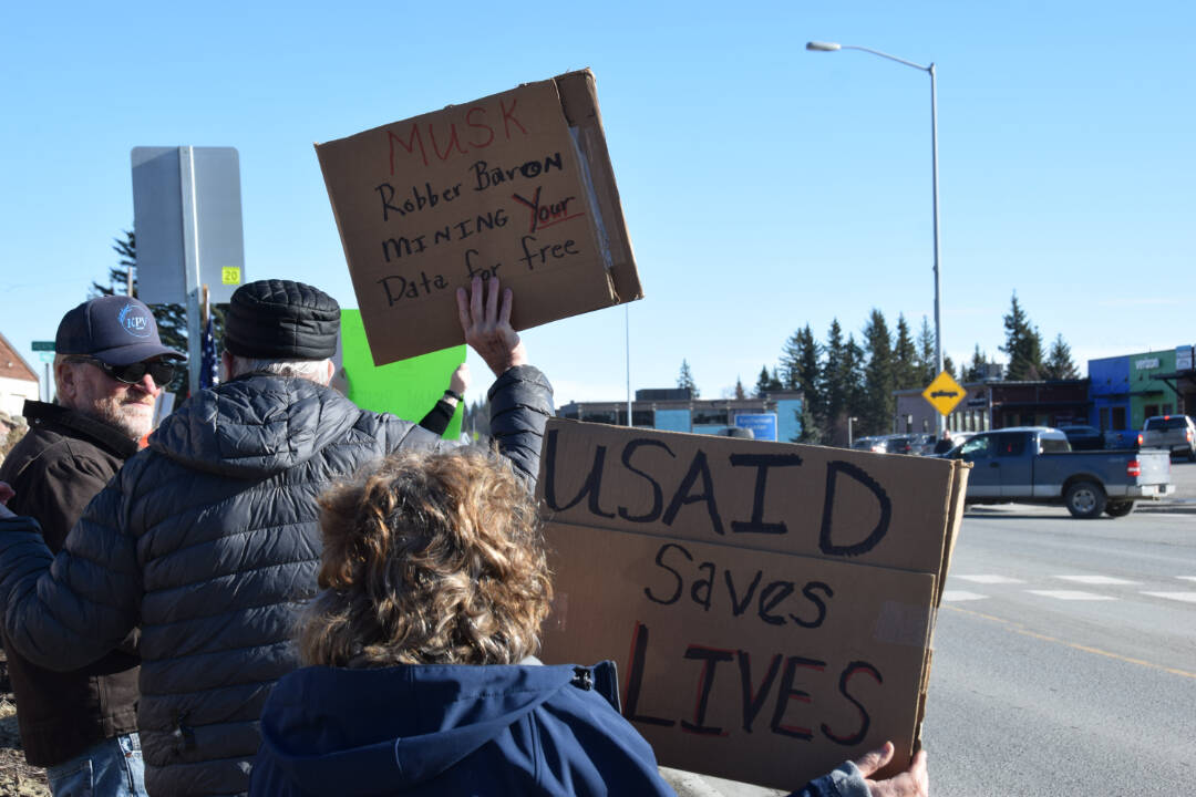 Community members hold up protest signs during the Stand for Democracy Rally on International Women’s Day, March 8, 2025, at WKFL Park in Homer, Alaska. (Chloe Pleznac/Homer News)