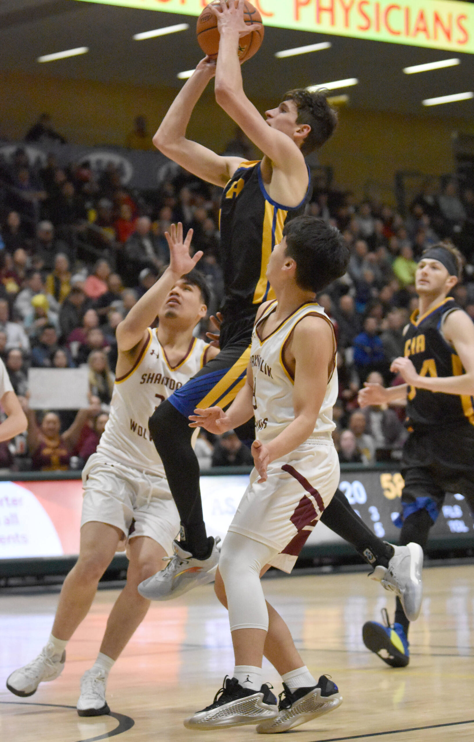 Cook Inlet Academy’s Alek McGarry slices between Shaktoolik’s Devin Rock and Austin Rock at the Class 1A boys state championship game Saturday, March 15, 2025, at the Alaska Airlines Center in Anchorage, Alaska. (Photo by Jeff Helminiak/Peninsula Clarion)