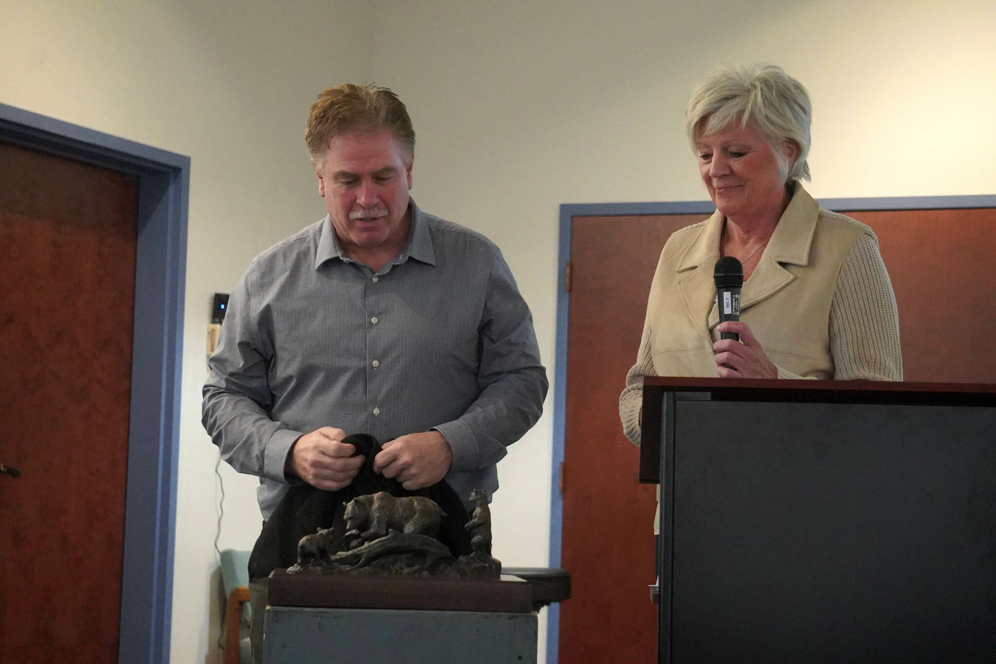 Kenai Mayor Brian Gabriel unveils a small model of the Kenai Bronze Bear Sculpture during a luncheon hosted by the Kenai Chamber of Commerce in Kenai, Alaska, on Wednesday, March 19, 2025. (Jake Dye/Peninsula Clarion)