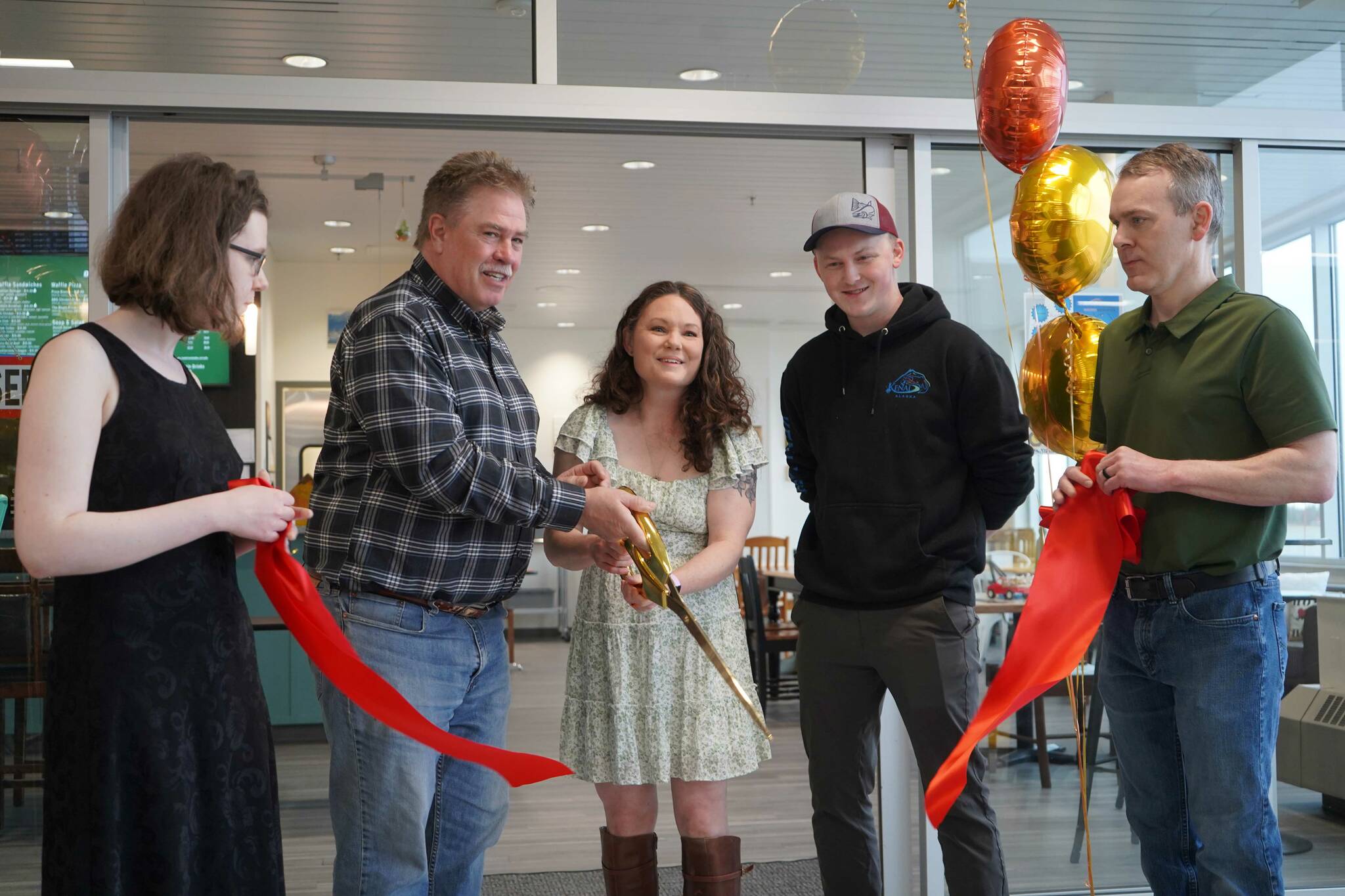 Debbie Adams joins Kenai Mayor Brian Gabriel in cutting a ribbon during the grand opening of Debbie’s Bistro in its new location in the Kenai Municipal Airport in Kenai, Alaska, on Saturday, April 5, 2025. (Jake Dye/Peninsula Clarion)