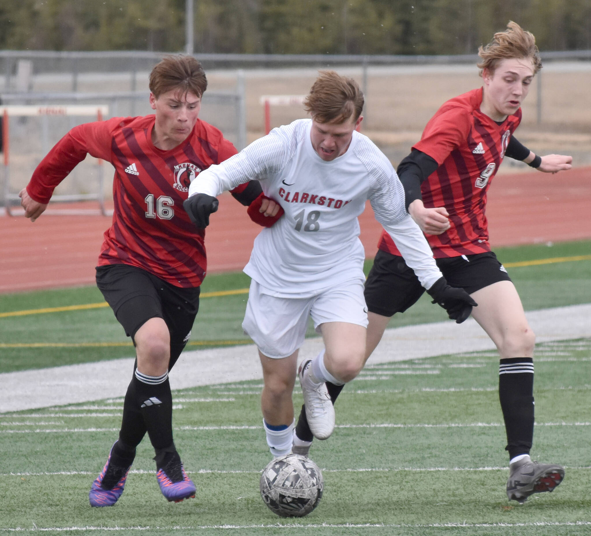 Stone Ausman of Clarkston (Washington) tries to split Sawyer Vann and Zane James of Kenai Central on Monday, April 7, 2025, at Ed Hollier Field at Kenai Central High School in Kenai, Alaska. (Photo by Jeff Helminiak/Peninsula Clarion)