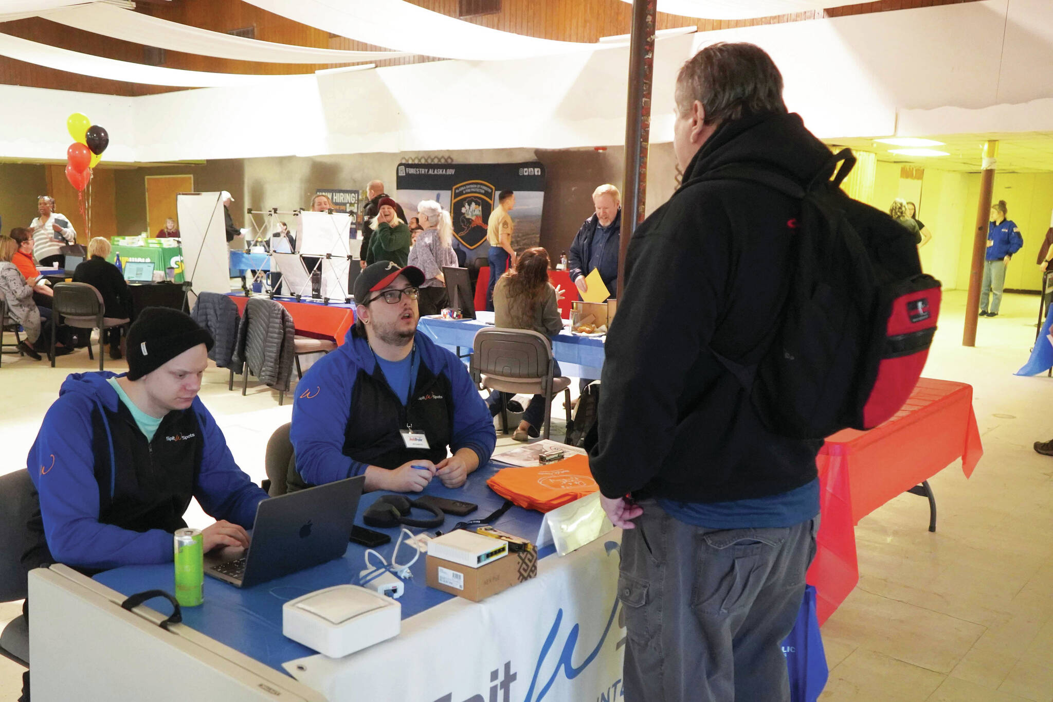 Jake Dye/Peninsula Clarion
SPITwSPOTS employees speak to an attendee of the Kenai Peninsula Job and Career Fair in Kenai on Wednesday.