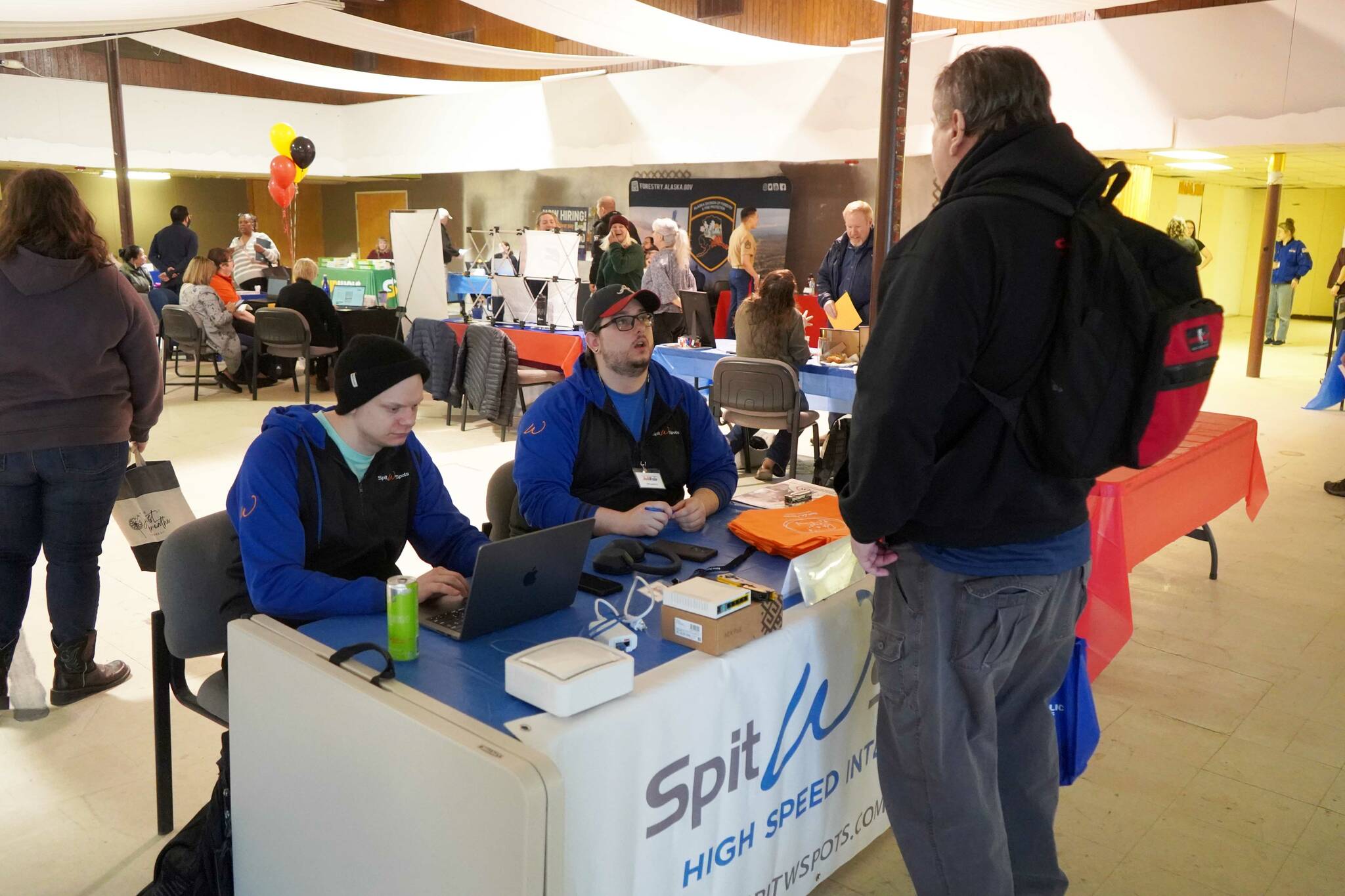 SPITwSPOTS employees speak to attendees of the Kenai Peninsula Job and Career Fair in Kenai, Alaska, on Wednesday, April 16, 2025. (Jake Dye/Peninsula Clarion)
