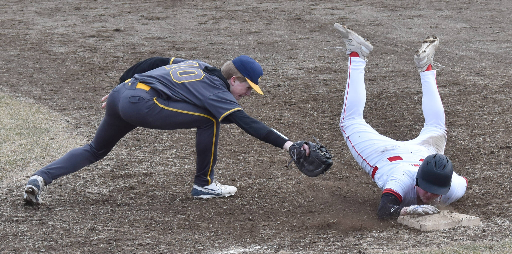 Kenai Central’s Gabe Joanis beats the tag of Homer’s Henry Wedvik on Friday, April 25, 2025, at the Kenai Little League fields in Kenai, Alaska. (Photo by Jeff Helminiak/Peninsula Clarion)