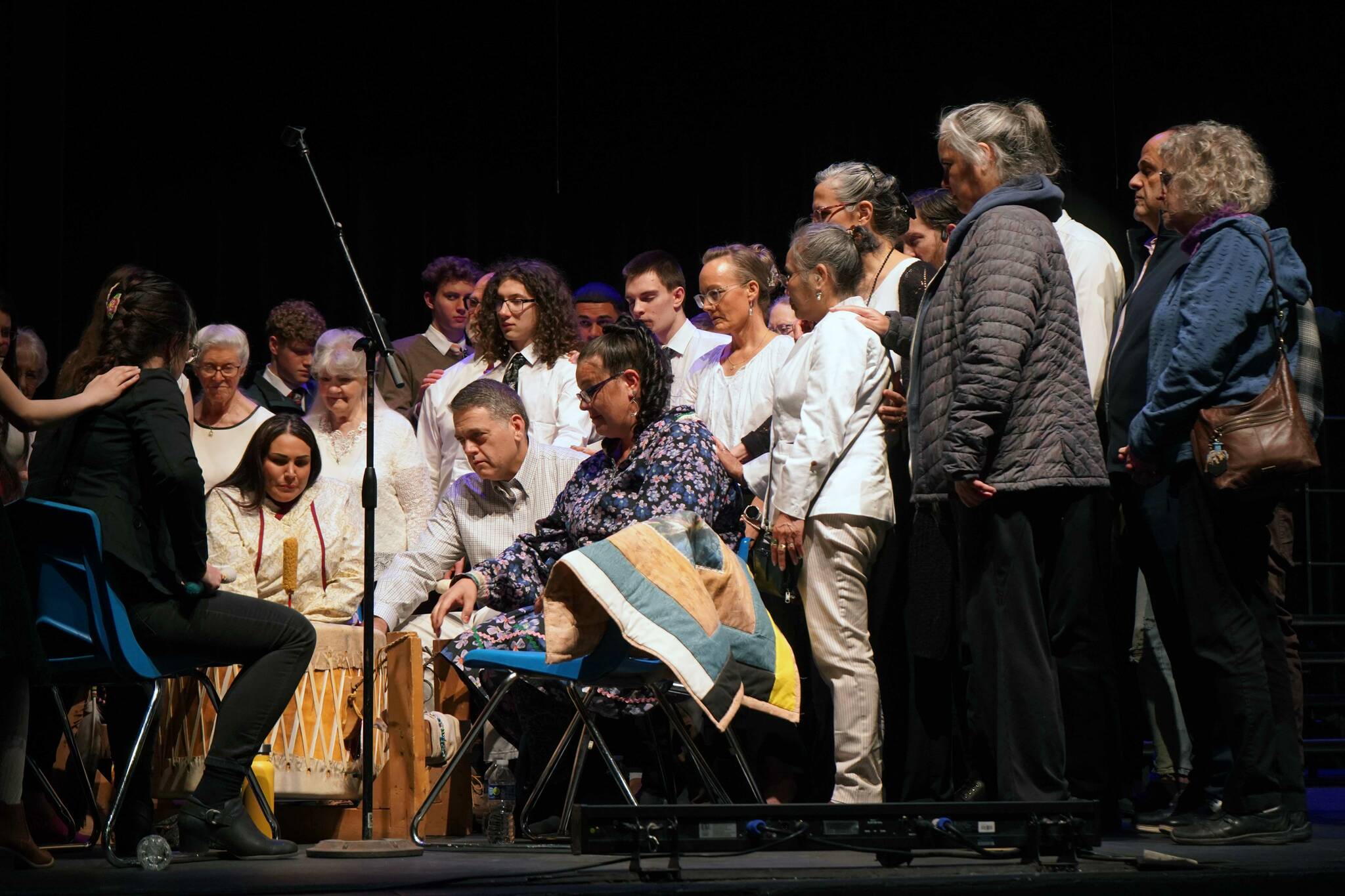 People from various faiths stand together at the conclusion of a prayer by the Kenaitze Indian Tribe’s Heartbeat of Mother Earth Drum group during a National Day of Prayer Celebration hosted by the KPen Interfaith Community at Soldotna High School in Soldotna, Alaska, on Thursday, May 1, 2025. (Jake Dye/Peninsula Clarion)