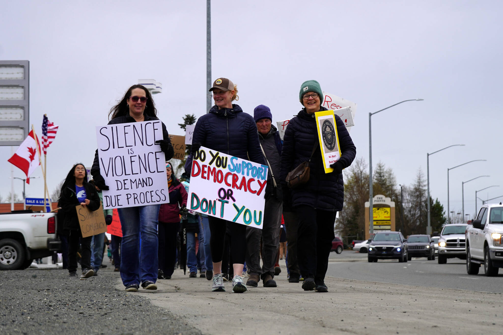 People carry signs and stand as part of a May Day protest alongside the Sterling Highway in Soldotna, Alaska, on Thursday, May 1, 2025. (Jake Dye/Peninsula Clarion)