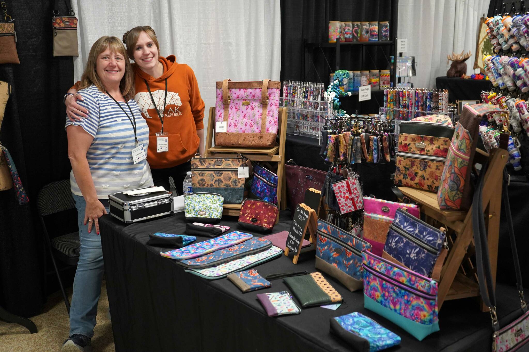 Kathy Waterbury and Tasha Dawson stand at their booths for Fireweed Stitches and Bear Mountain Designs during the 38th Annual Kenai Peninsula Sport, Rec & Trade Show at the Soldotna Regional Sports Complex in Soldotna, Alaska, on Friday, May 2, 2025. (Jake Dye/Peninsula Clarion)