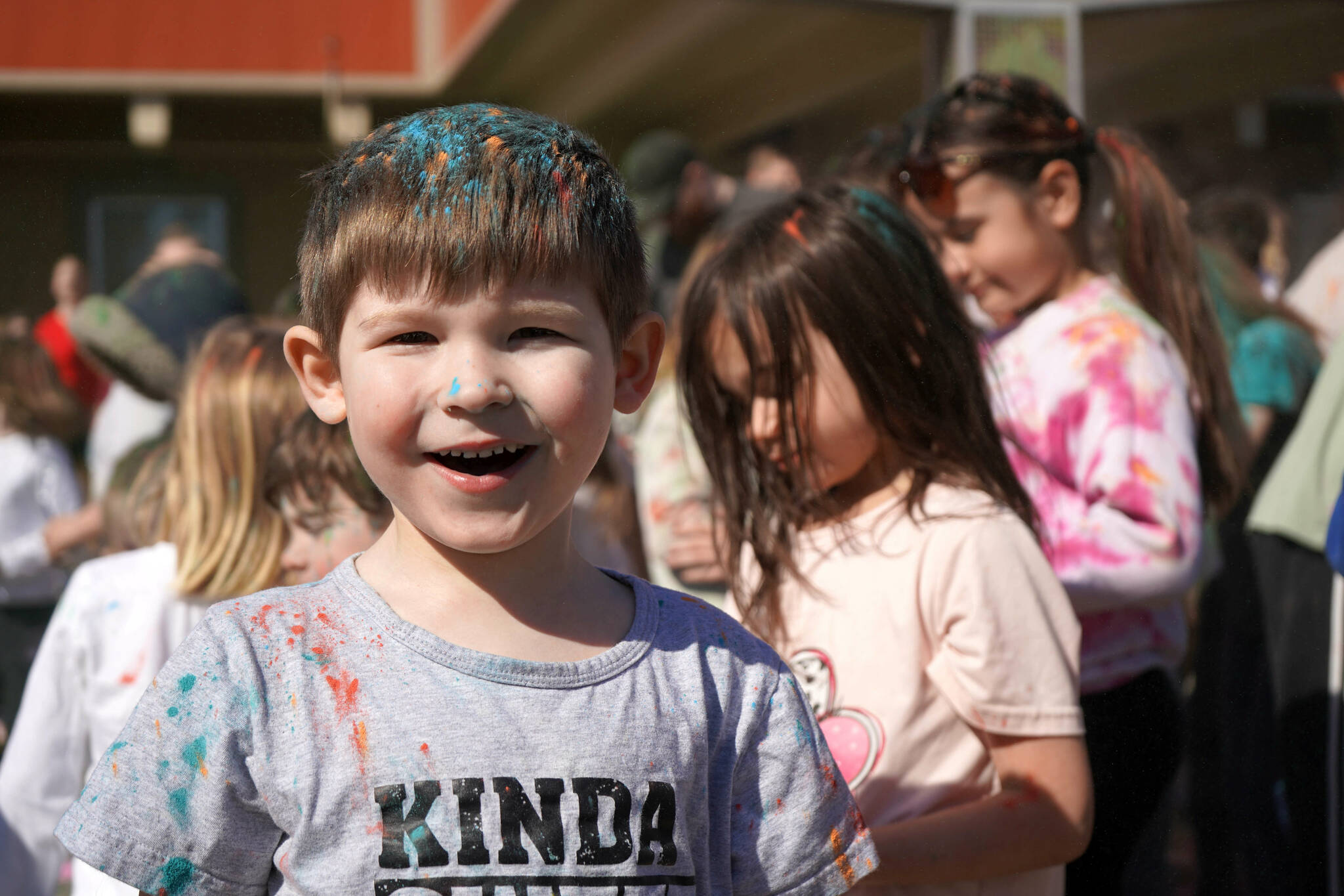Students are covered in brightly hued powder during a color run at Kaleidoscope School of Arts and Science in Kenai, Alaska, on Saturday, May 3, 2025. (Jake Dye/Peninsula Clarion)