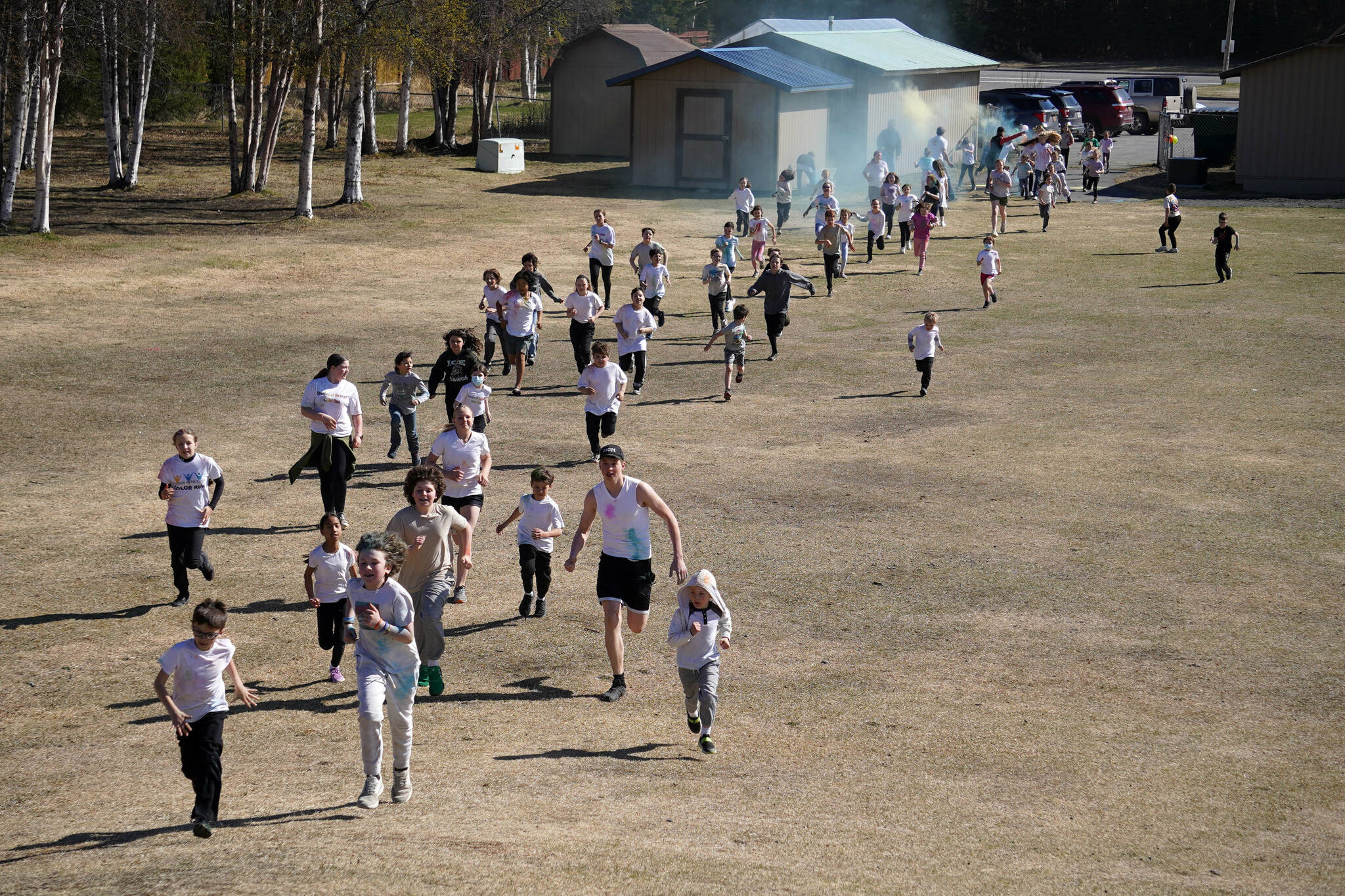 Students are covered in brightly hued powder during a color run at Kaleidoscope School of Arts and Science in Kenai, Alaska, on Saturday, May 3, 2025. (Jake Dye/Peninsula Clarion)