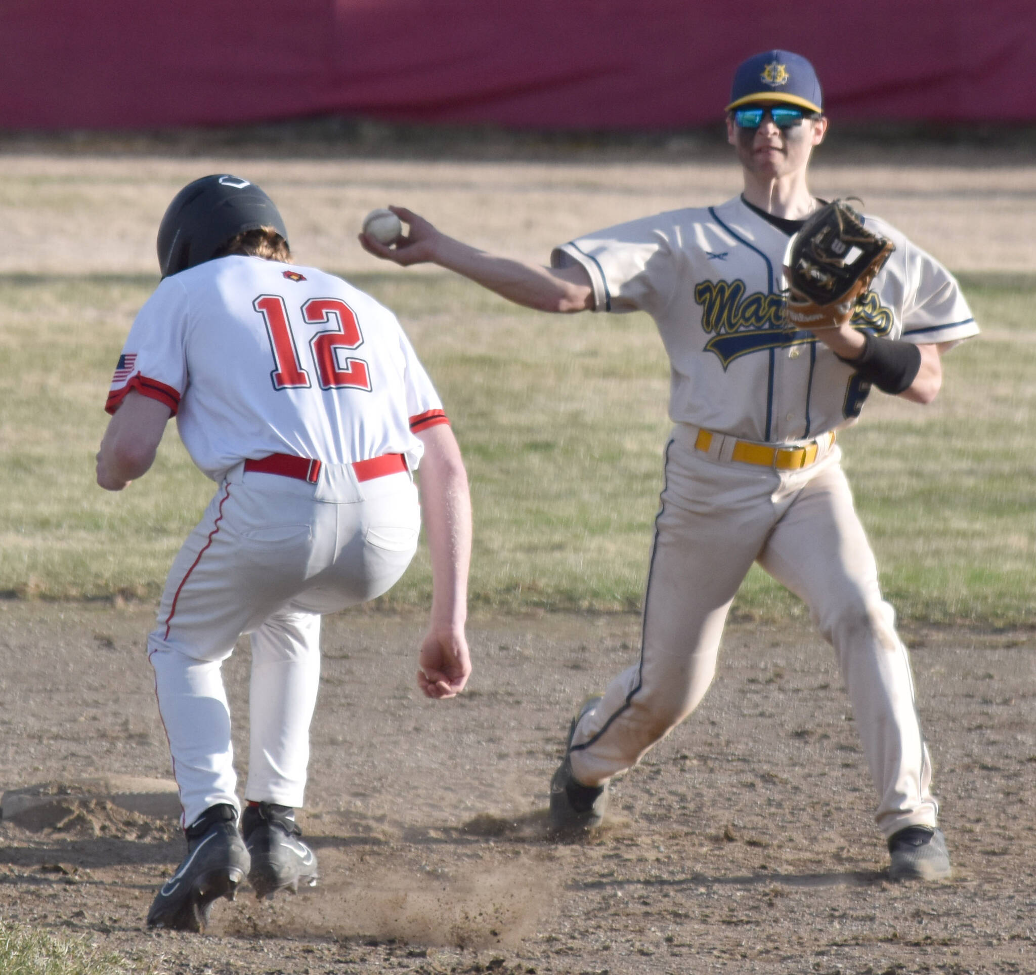 Homer second baseman Austin Briscoe turns a double play in front of Kenai Central’s Avery Martin on Friday, May 9, 2025, at the Kenai Little League fields in Kenai, Alaska. (Photo by Jeff Helminiak/Peninsula Clarion)