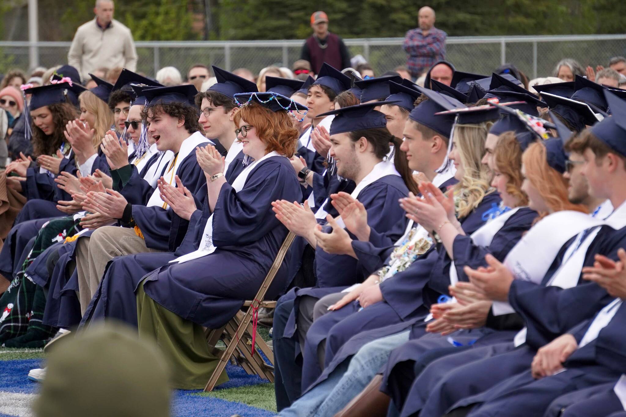 Graduates of Soldotna High School applaud during a commencement ceremony on the school’s football field in Soldotna, Alaska, on Wednesday, May 21, 2025. (Jake Dye/Peninsula Clarion)