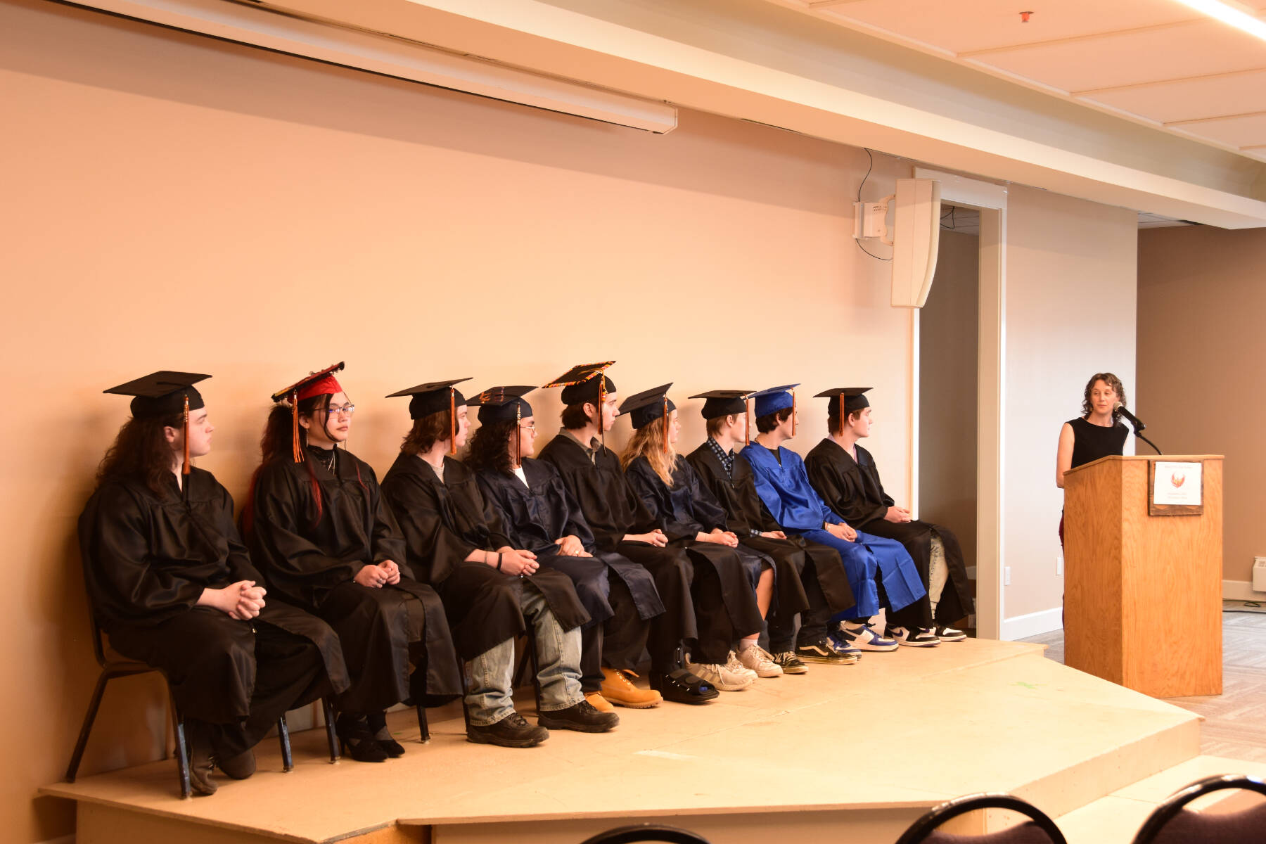 Homer Flex counselor Sue Rennolds (right) speaks to the graduating class of 2025 during the commencement ceremony held Wednesday, May 21, 2025, at Land’s End Resort in Homer, Alaska. (Delcenia Cosman/Homer News)